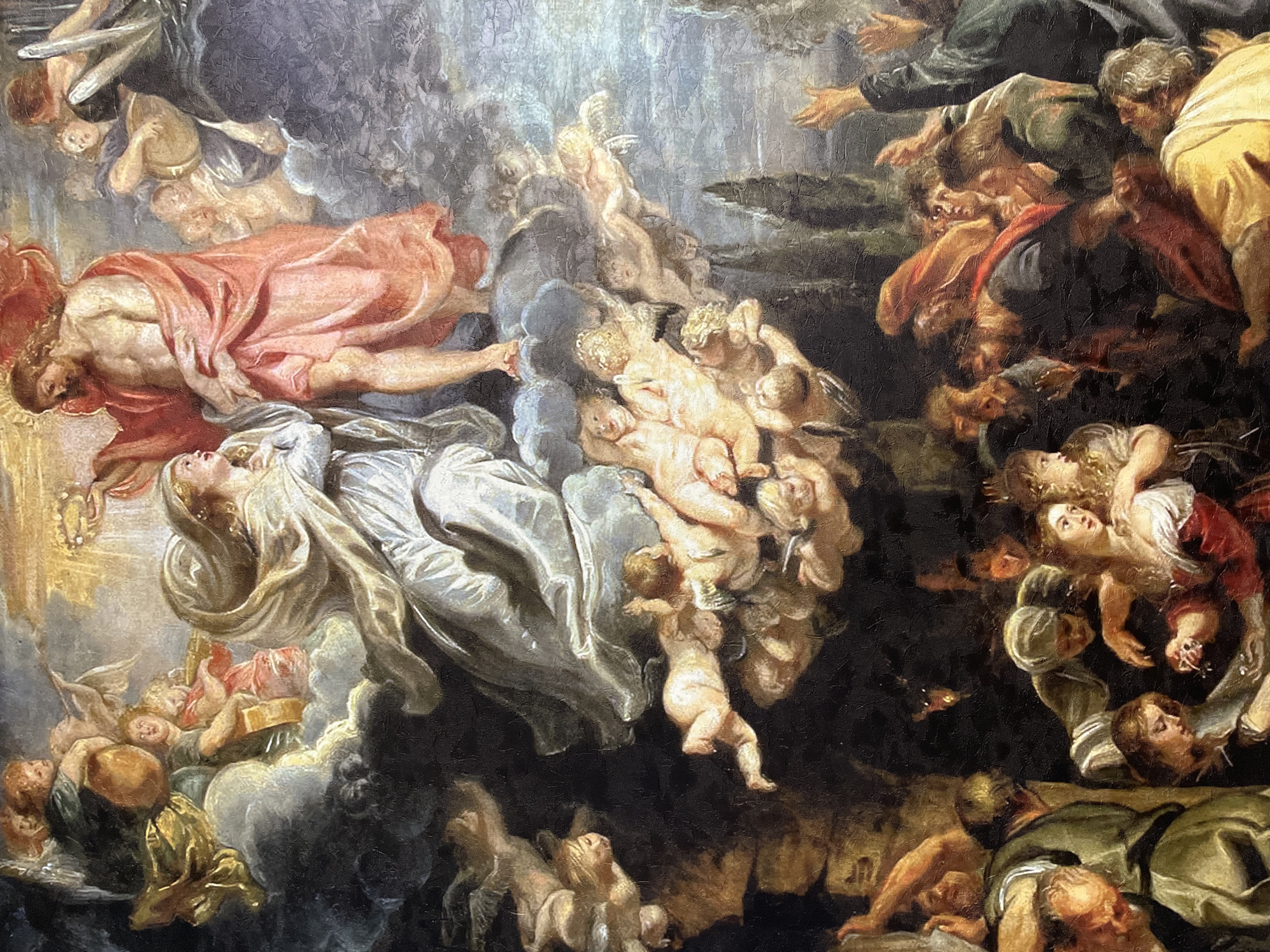This Baroque-style painting depicts a dramatic religious scene combining elements of ascension and judgment. The composition is vertically divided, contrasting a luminous heavenly realm with a darker, tumultuous earthly or infernal domain.
In the upper-left and central sections, a serene female figure, likely the Virgin Mary, is shown ascending, her gaze directed upwards. She is draped in white and supported by numerous putti and clouds. Above her, a muscular male figure in flowing pink drapery also ascends, looking down at the scene below. A multitude of cherubs and putti fill the air, contributing to the sense of divine movement and grace.
The lower and right portions of the painting are populated by a large crowd of earthly figures. These men and women display a range of intense emotions, including awe, despair, fear, and struggle. Some look upwards in supplication or bewilderment, while others appear to be falling or caught in a chaotic descent into darkness. Their bodies are intertwined, and their faces are contorted with anguish, creating a stark contrast with the serene ascension occurring above.
The lighting is highly dramatic, with bright, ethereal light illuminating the ascending figures and deep shadows engulfing the distressed figures below, emphasizing the spiritual division. The overall activity portrays a moment of divine intervention, possibly an Assumption or a Last Judgment, separating the blessed from the damned. There is no visible text in the image, and no specific geographical or time-of-day cues are present beyond the implied sacred setting.