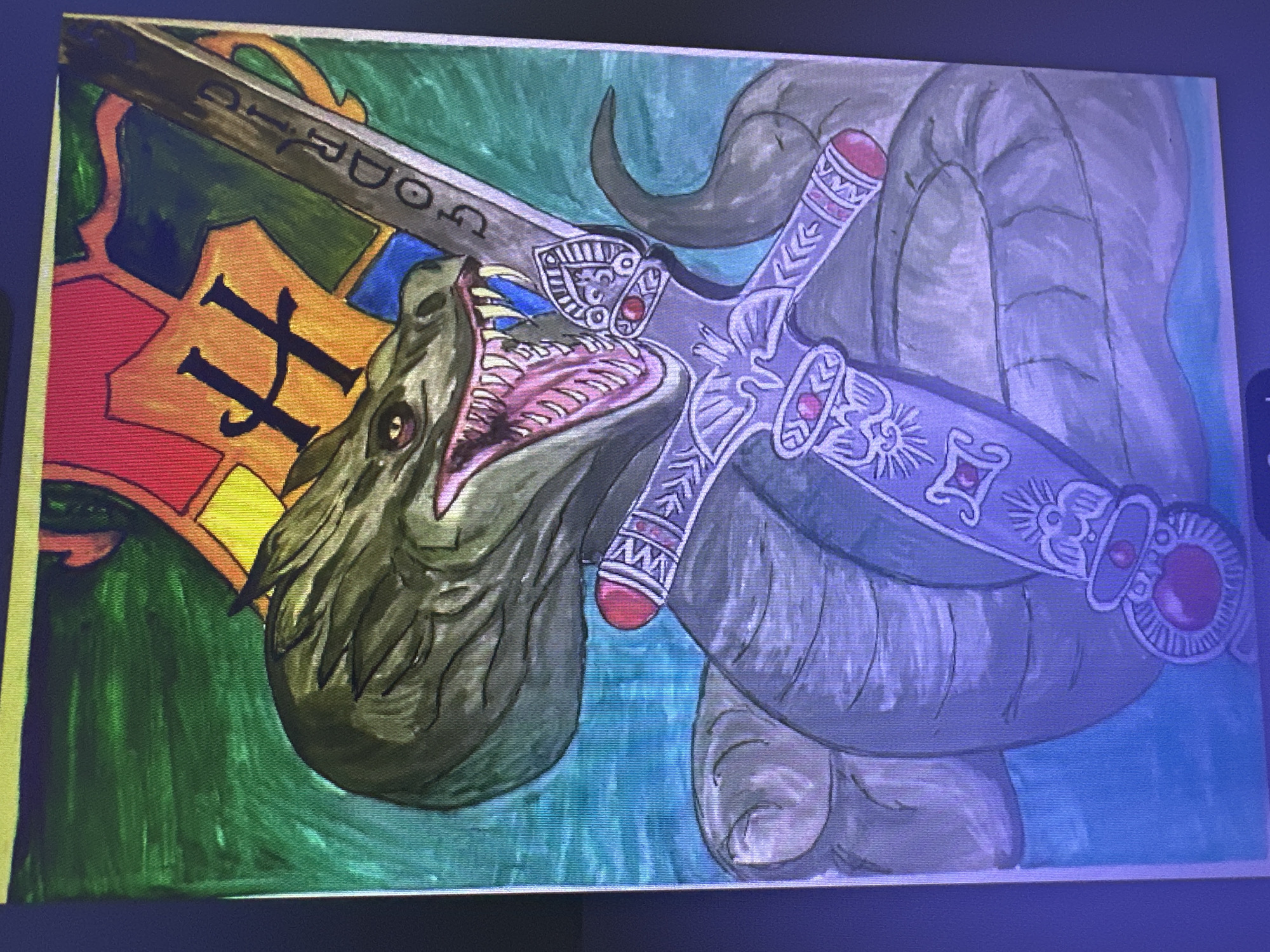 The image is a painting of a dragon-like creature with its mouth open, revealing sharp teeth. The creature is coiled around a decorative sword. In the background, there is a colorful banner with a stylized letter "H" and other geometric shapes. The colors used are vibrant, with greens, blues, reds, oranges, and yellows. The painting style appears to be watercolor or acrylic. The image does not contain any information about the city of Mineralnye Vody, Russia.
