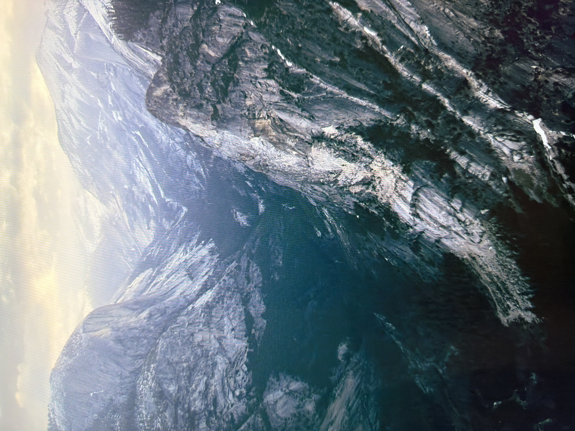The image depicts a vast, mountainous landscape, likely a national park or wilderness area. The terrain is characterized by steep, rocky cliffs and a deep, shadowed valley filled with dense coniferous trees. The upper slopes of the mountains are dusted with snow, and the sky above is bright and hazy, suggesting either dawn, dusk, or overcast conditions. The overall impression is one of natural grandeur and rugged, untamed beauty.
The query specifies the location as Kyiv, Ukraine. However, the image provided does not show any identifiable landmarks or features characteristic of the city of Kyiv. Instead, it presents a remote, mountainous environment that is inconsistent with the urban geography of Kyiv. Therefore, it is not possible to provide details about the location within Kyiv based on the visual information in the image.