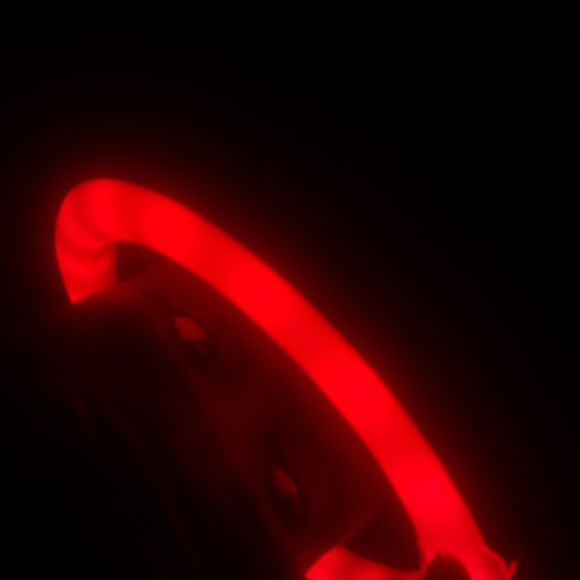 The image shows a red, glowing ring-shaped object in a dark environment. The object appears to be held by someone, but only their blurred silhouette is visible due to the low lighting. The background is entirely black. There are no discernible details to indicate the location as Narayi, Nigeria, or any specific city.