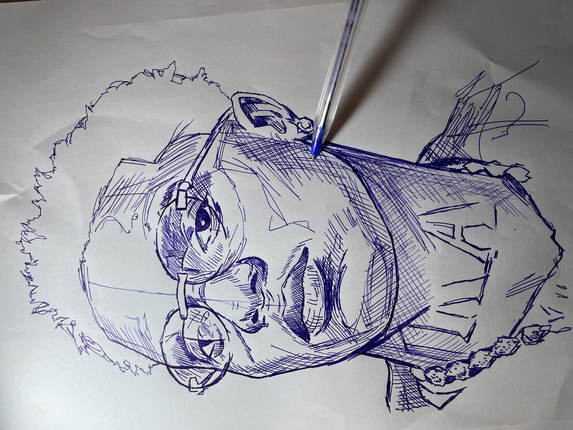 This is a close-up, head-and-shoulders pen and ink drawing of a young Black man. The drawing is rendered in a sketch style with visible cross-hatching for shading. The subject is wearing round-rimmed glasses, a chain necklace with large links, and an earring. His hair is short and textured, and his mouth is slightly open. The drawing is executed on white paper. A blue ballpoint pen is partially visible in the lower right corner of the image, with its tip touching the drawing on the subject's cheek. There is no indication of a specific location in the city of Jos, Nigeria, within the provided image or its crops.