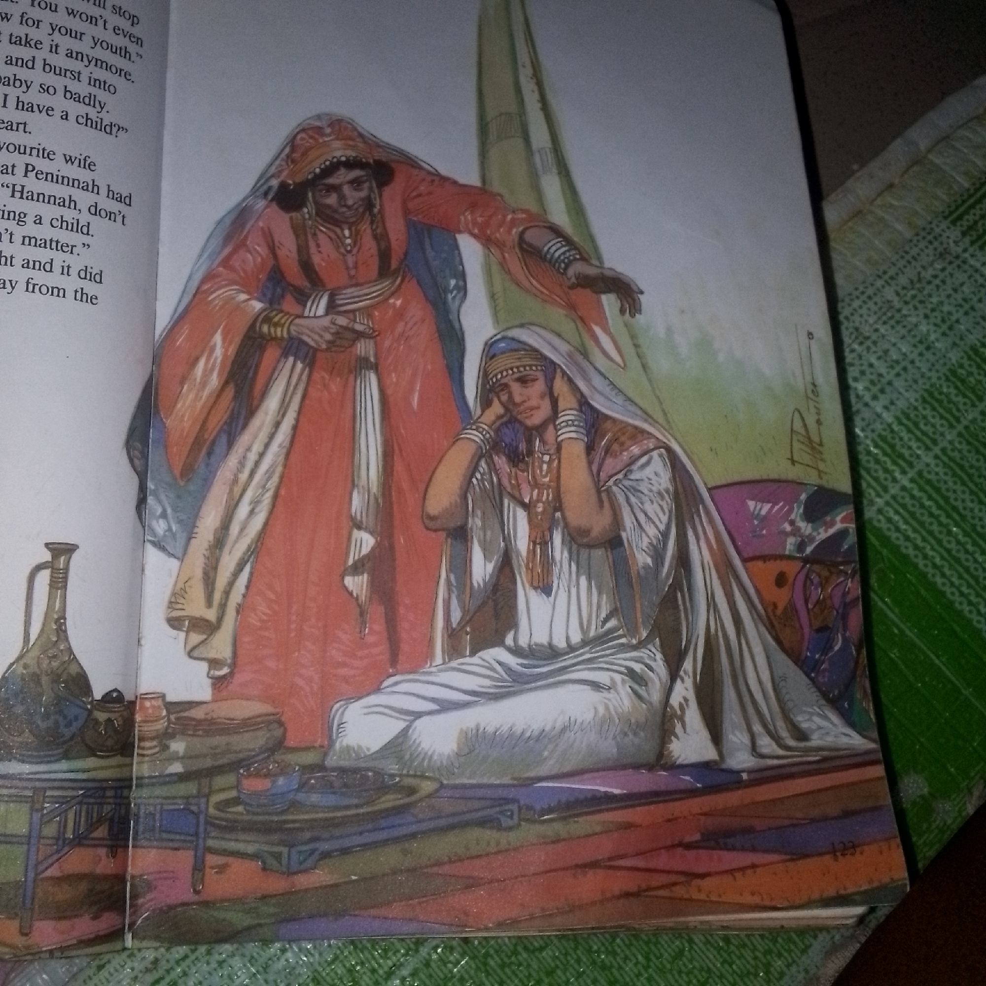 The image depicts two women dressed in historical attire. The woman on the left wears a reddish-orange robe with intricate gold trim and a matching headscarf, her arm extended and hand open as if in mid-gesture or to comfort. The woman on the right is seated and dressed in a white robe and head covering, her hands covering her ears and her head bowed, suggesting distress or unwillingness to listen. They are positioned within a room with a visible portion of text to the left of the illustration, indicating it is from a book or manuscript. The background features a draped fabric in shades of green and yellow. In the foreground, a low table holds various ceramic vessels, including a jug with a handle and smaller pots and bowls. The floor is decorated with a colorful, segmented pattern. The scene is brightly lit, with the overall style suggesting an illustration from a narrative or historical text. The precise location and city are not specified in the image.