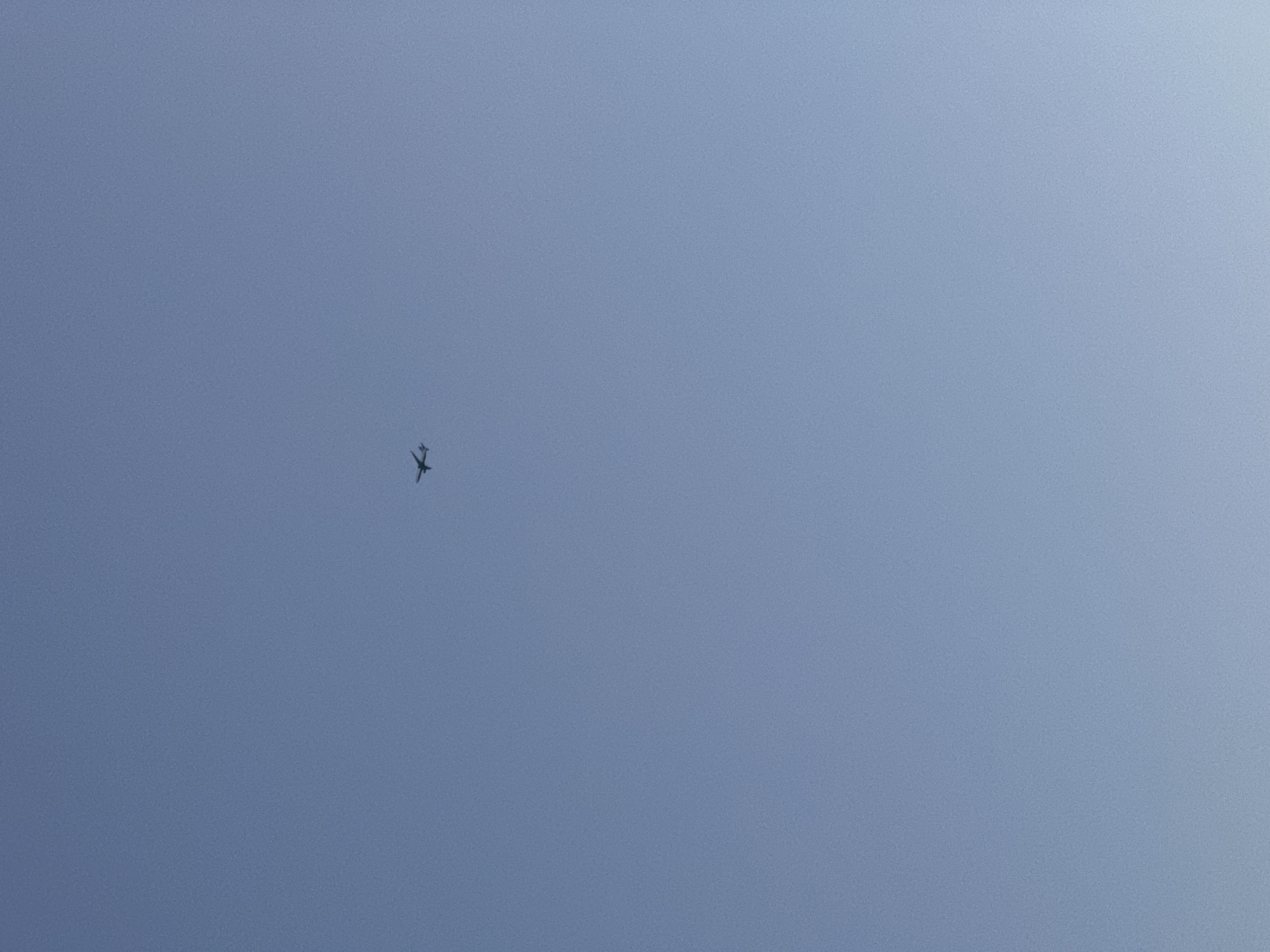The image shows an airplane flying in a clear, blue sky. The location is not determinable from the image itself. There are no people or other objects visible.