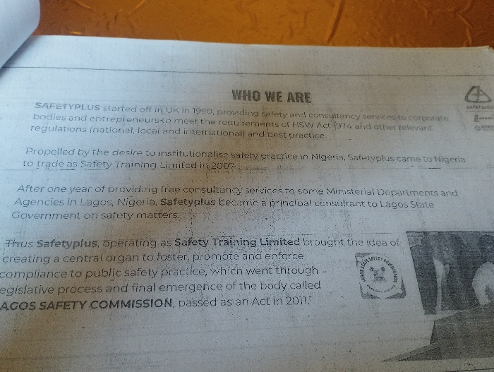 The image is a close-up of a page from a document titled "WHO WE ARE." The document is about the history and work of Safetyplus, a company that provides safety and consultancy services to corporations and entrepreneurs in Nigeria. The text details how Safetyplus started in the UK in 1990 and came to Nigeria to trade as Safety Training Limited in 2008. It mentions that Safetyplus provided free consultancy services to some ministerial departments and agencies in Lagos, Nigeria, and became a principal consultant to Lagos State Government on safety matters. The document goes on to say that Safetyplus brought the idea of creating a central organ to foster, promote and enforce compliance to public safety practice, which went through the legislative process and final emergence of the body called Lagos Safety Commission, passed as an Act in 2011. There is a small logo in the lower right corner of the image, depicting a shield with a safety helmet design and the words "Lagos Safety Commission" written around it. The image is of a page from a document that appears to be printed on a plain white paper. The coordinates provided (10.917, 11.475) are not relevant to the image and correspond to a location in the city of Ashaka, Nigeria. The image shows only the document and no people.