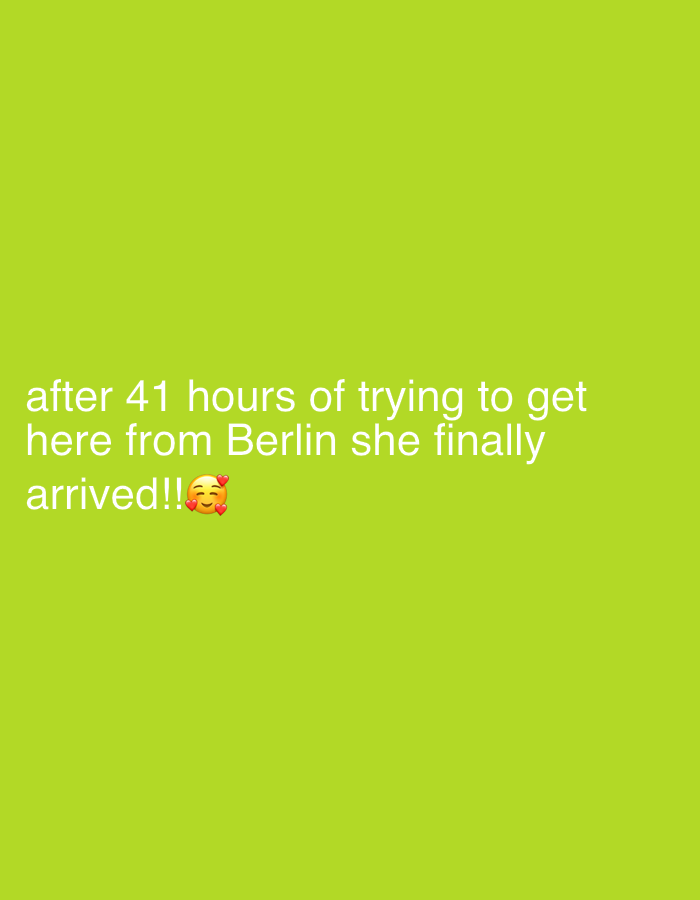 The image displays a solid, uniform lime green background. Positioned in the lower-left quadrant is white sans-serif text stating: "after 41 hours of trying to get here from Berlin she finally arrived!!". Immediately following the text "arrived!!" is a single emoji depicting a yellow face with closed, smiling eyes and three red hearts floating above it. No people, subjects, objects, or specific environmental features are visually depicted. The text indicates an arrival at an unspecified location referred to as "here," following travel from Berlin. The image contains no visual or textual information to identify "here" as the city of Nesso, Italy, or any specific location within it.