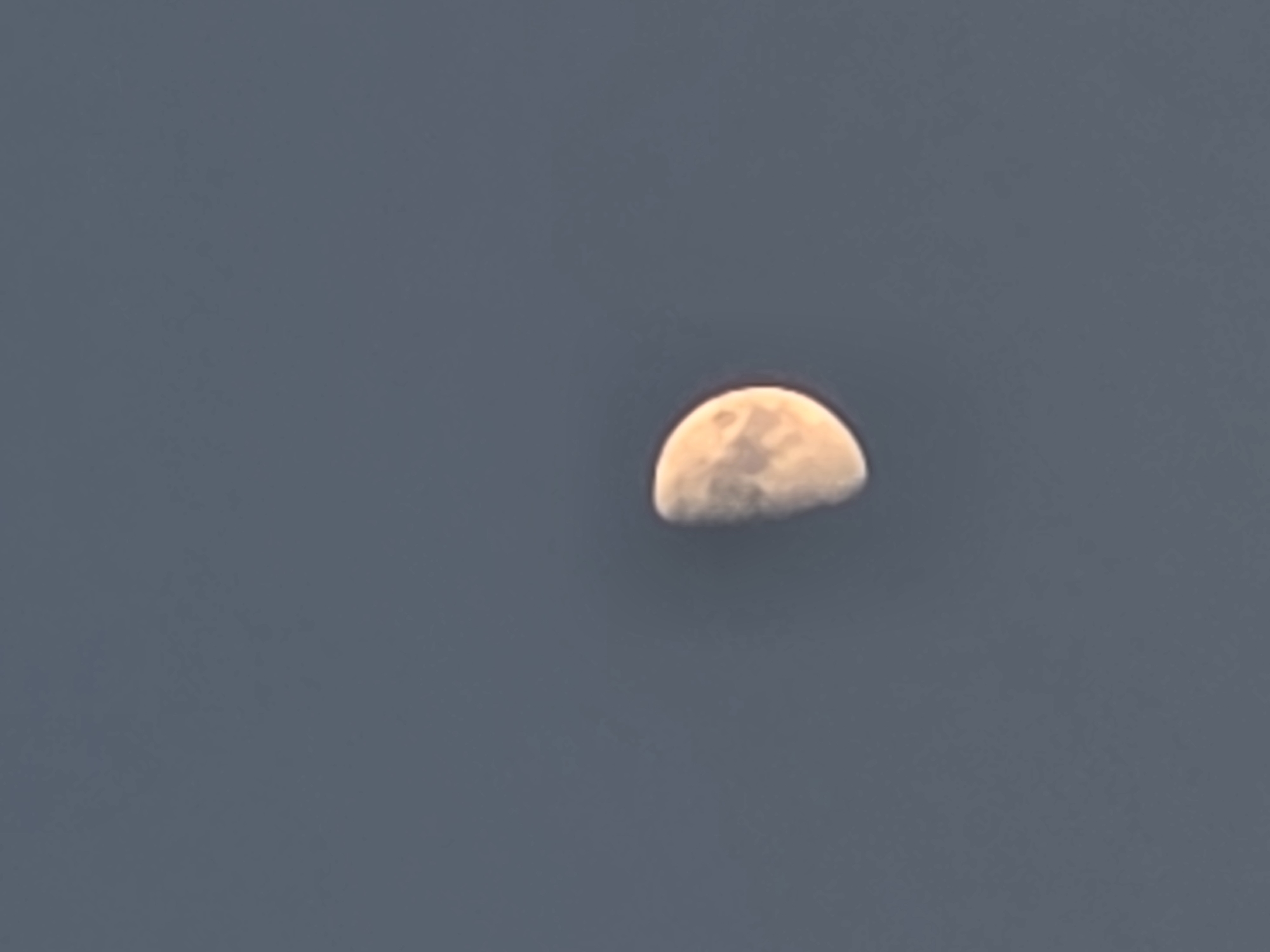 A half-moon is visible against a clear, dark blue sky. The moon is illuminated on its right side, showing some surface detail. The image is taken from a distance, with no other objects or landmarks visible. The exact location in Verona, Italy, cannot be determined from the provided image.