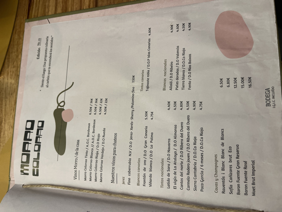 A menu from a restaurant named "Morro Colorado" is presented. It is printed on a white paper, and the text is black, with some prices highlighted in red. The menu lists various wines, including whites, reds, and sparkling wines. The wines are categorized by origin and type. Some wines are labeled as "our wines for tapas." An image of a red, white, and black heart-shaped design is in the top left corner. The menu is from the restaurant Morro Colorado, located in Las Palmas de Gran Canaria, Spain (28.102, -15.414).