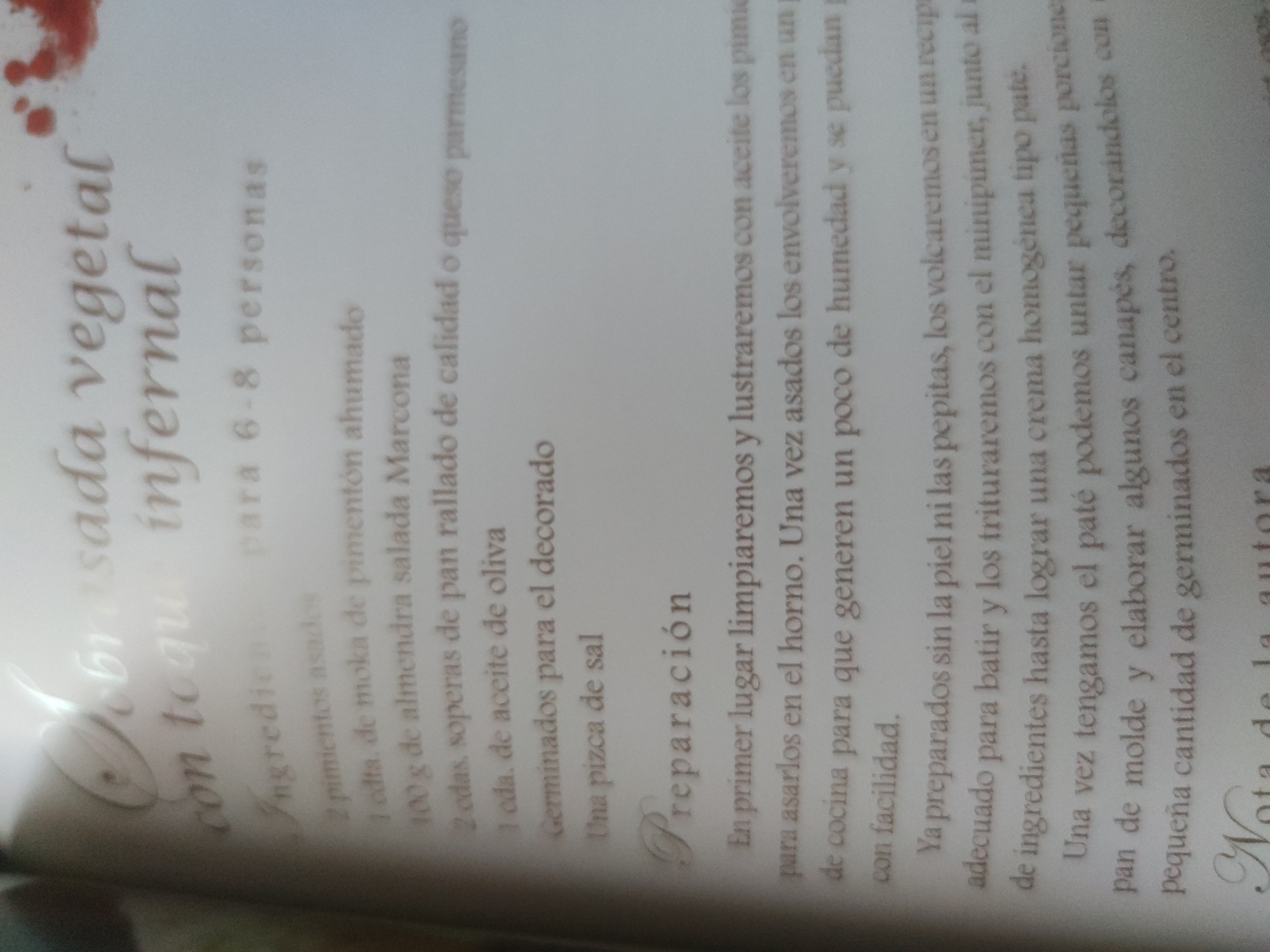 The image is a close-up, slightly blurry photograph of a recipe written in Spanish. The title of the recipe is "Dobrasada vegetal con toque infernal" (Vegetable Dobrasada with an Infernal Touch). It lists ingredients for 6-8 people, including roasted peppers, smoked paprika, Marcona almonds, breadcrumbs or Parmesan cheese, olive oil, sprouts for decoration, and salt. The preparation section gives instructions on how to make the recipe, including roasting the peppers, blending the ingredients to a pate, and using it as a spread on canapés.
