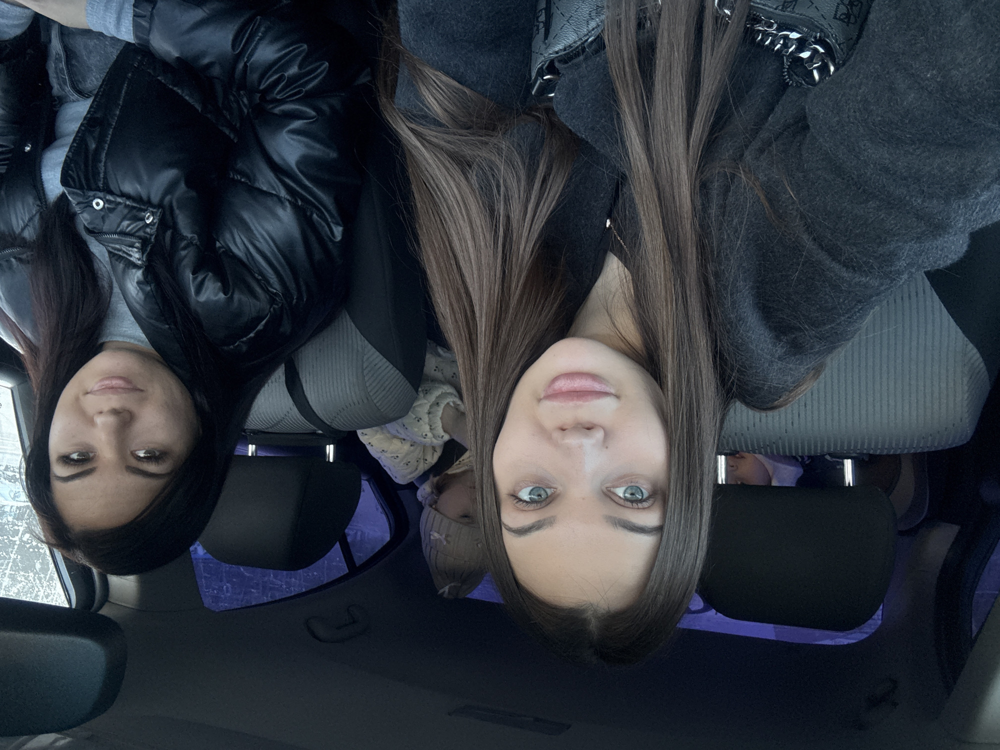 Two women are sitting in the front seats of a car. A child is visible in the back seat between the women. The photo appears to be taken from inside the car looking up. The location of the image is Chaikovsky, Russia.