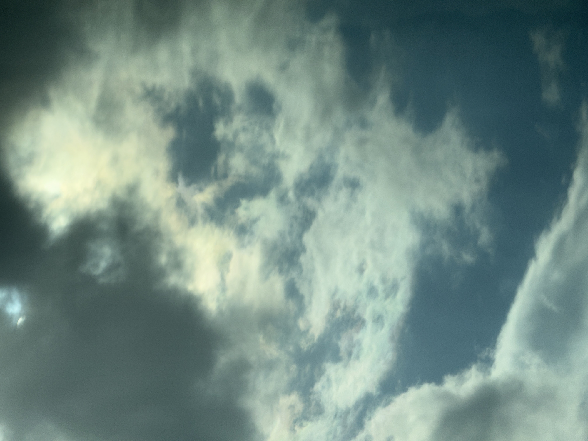 The image shows a cloudy sky. The clouds vary in color from dark gray to light gray and white. There is a patch of blue sky visible between the clouds. The location, Лиски, Russia, is not evident from the image itself. There are no people, subjects, objects, actions, or interactions visible in the image beyond the clouds.