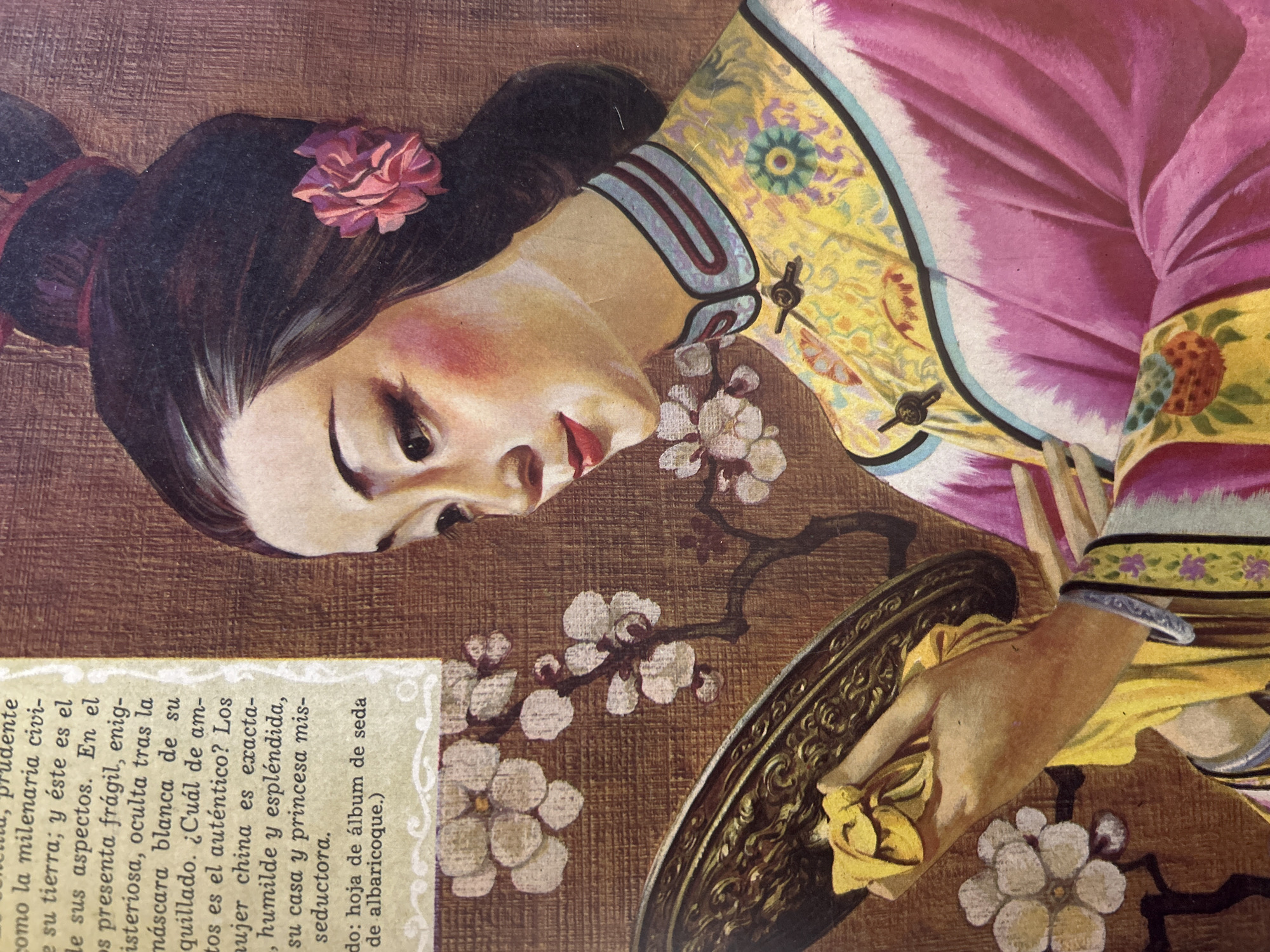 The image is a painting of a young East Asian woman in traditional Chinese attire. She has dark hair styled in a bun with a pink flower accessory. Her makeup is pronounced with rosy cheeks and bright red lipstick. She is looking down and to her right, holding a golden hand mirror and a yellow cloth in her hands. The background depicts a branch with white blossoms and has a textured, brownish appearance. The woman is wearing a yellow garment with intricate floral patterns and a pink outer robe. The image appears to be a vintage illustration, possibly from a magazine or book. The mention of "Santa Ana, Venezuela" is not supported by any visual elements within the provided image. There are no identifiable landmarks, cityscapes, or any context that would place the scene in that specific location.