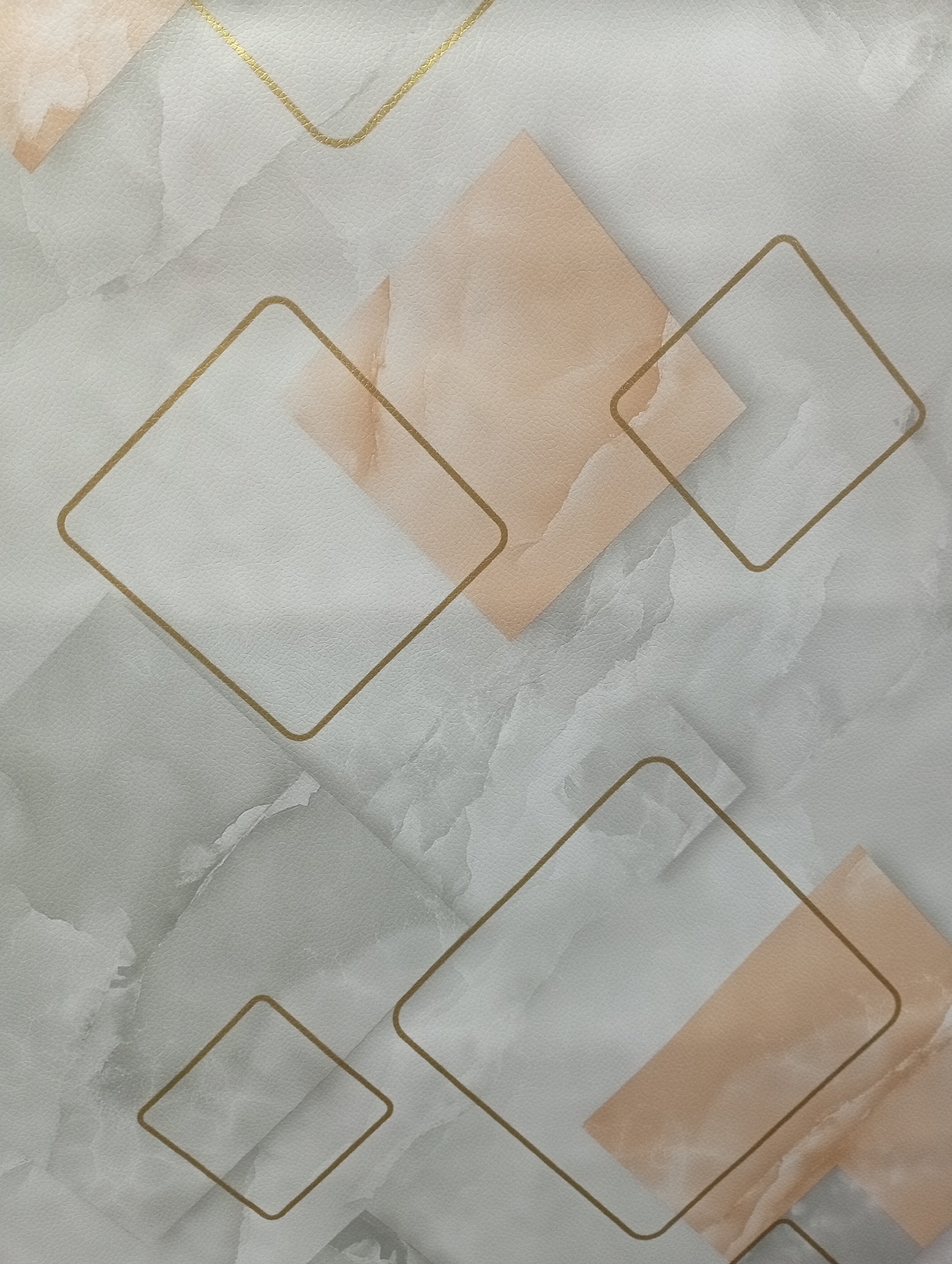 This is a close-up, straight-on shot of a wall with a patterned wallpaper. The wallpaper features a marble-like texture in shades of white, grey, and light peach. Overlaid on this base are abstract geometric shapes, primarily rhombuses outlined in a thin, metallic gold line. Some of the rhombuses are filled with a soft peach color, while others are filled with the grey and white marble pattern. The overall impression is modern and elegant. There are no people or specific landmarks visible. This image likely depicts an interior design element in a residential or commercial space. The location in Borovichi, Russia is not discernable from the visual information provided in the image.