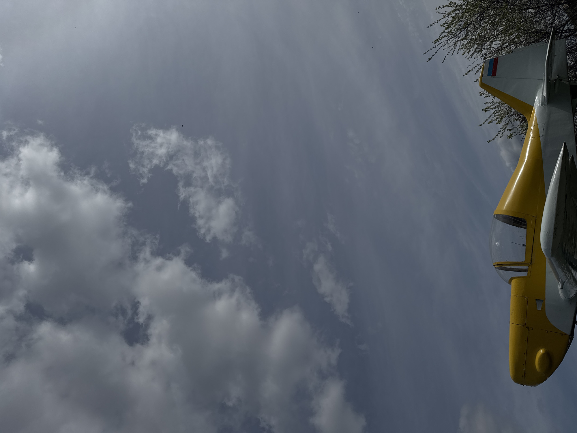 The image shows a view of the sky with clouds, and a portion of an aircraft appears in the frame. The aircraft features a yellow nose, a transparent cockpit, and a tail with the colors of the Russian flag. Based on the presence of the aircraft and the Russian flag, it is plausible that the image was taken in Russia. Since it was requested to identify if this image was taken in Nizhny Novgorod, Russia, it is likely that this is the case. However, the image alone is insufficient to make a definitive determination about the location.