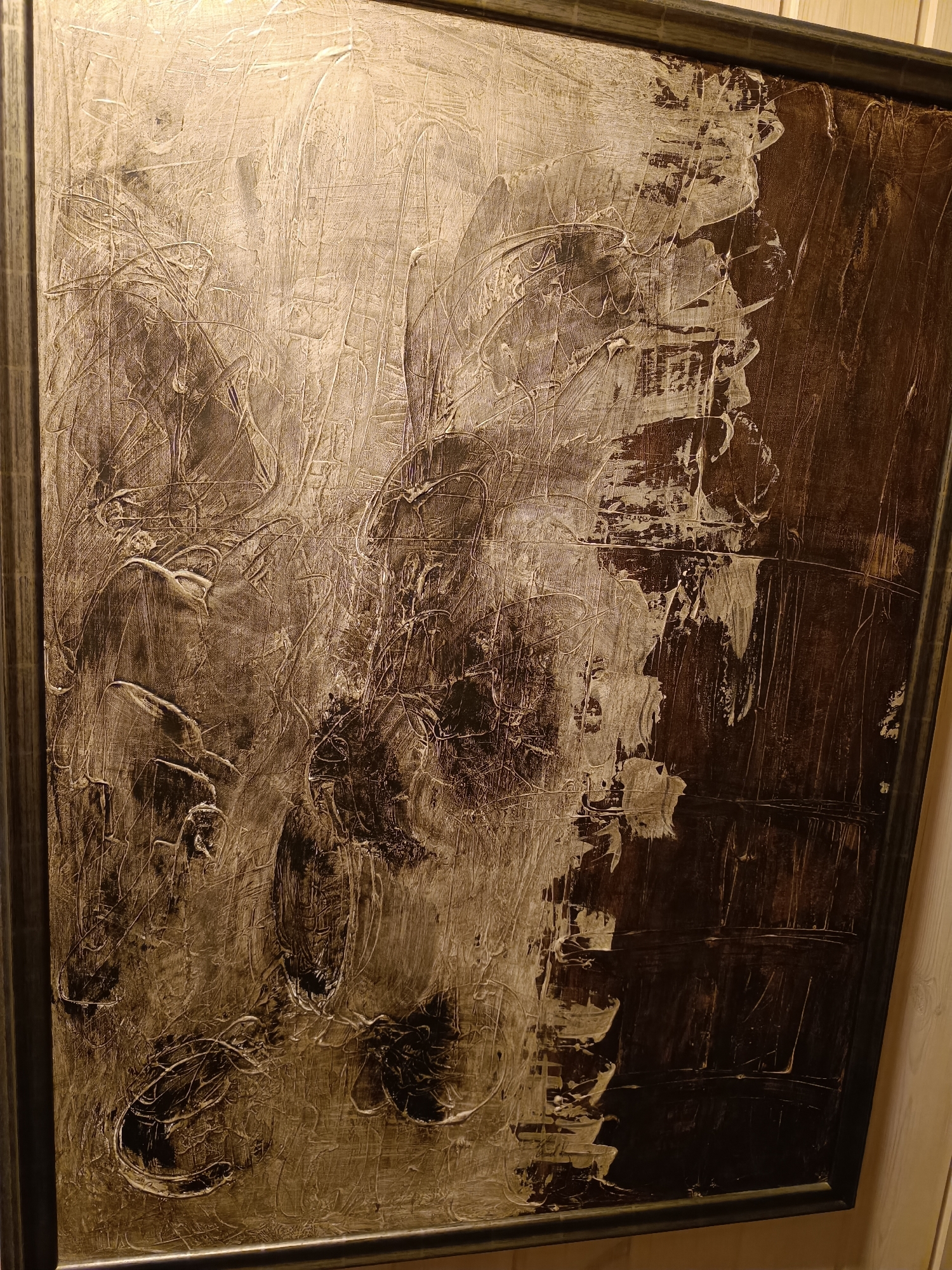 The image displays an abstract painting with a textured surface. The painting is framed and appears to be hanging on a wall. The colors are predominantly earthy tones, with shades of brown, beige, and white. The brushstrokes are visible, creating a sense of depth and movement. The overall impression is one of dramatic contrast and dynamic energy. The location provided, Hovden, Norway, offers a geographical context but is not visually represented within the artwork itself. There are no people, actions, or interactions depicted in the image.