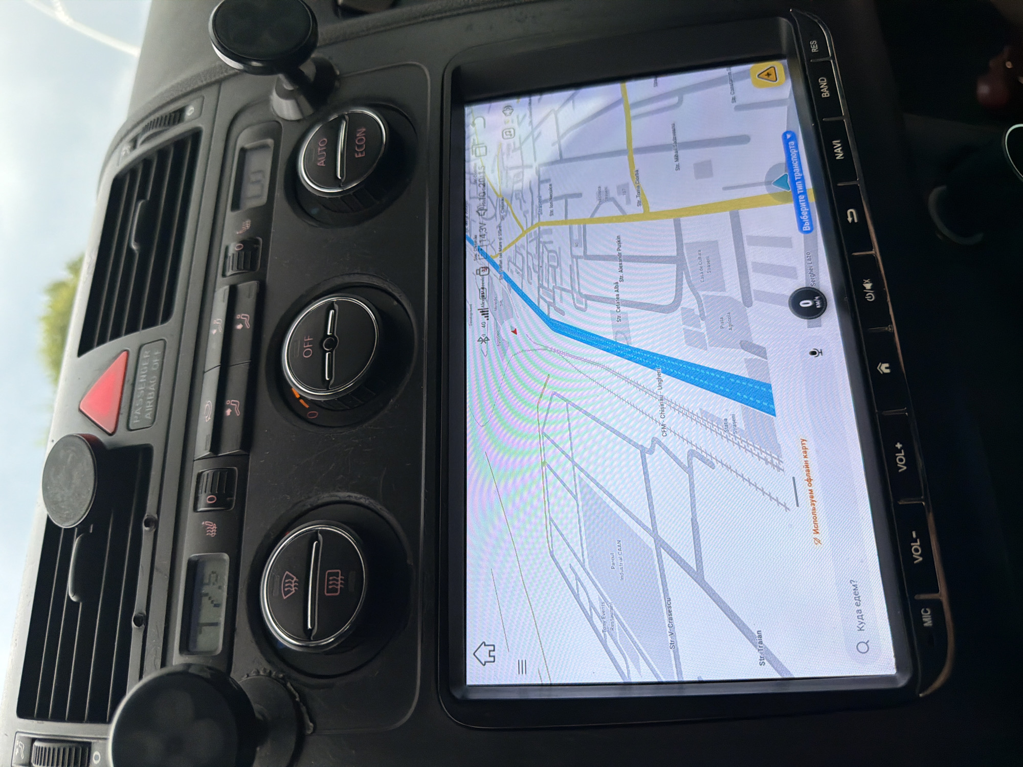 The image shows the interior of a car, focusing on the dashboard and the infotainment screen. The dashboard features several control knobs and buttons, including those for climate control and hazard lights. A digital display shows "72.5", likely the outside temperature. The infotainment screen displays a map with navigation. Several streets are visible, including "Str. V. Crascescu" and "Str. Traian". The map also indicates a location named "CFM - Chisinau - Ungheni", which is a railway station in Moldova, and a town named "Strășeni" is also visible on the map. The overall environment suggests the car is in transit, with the navigation system active.