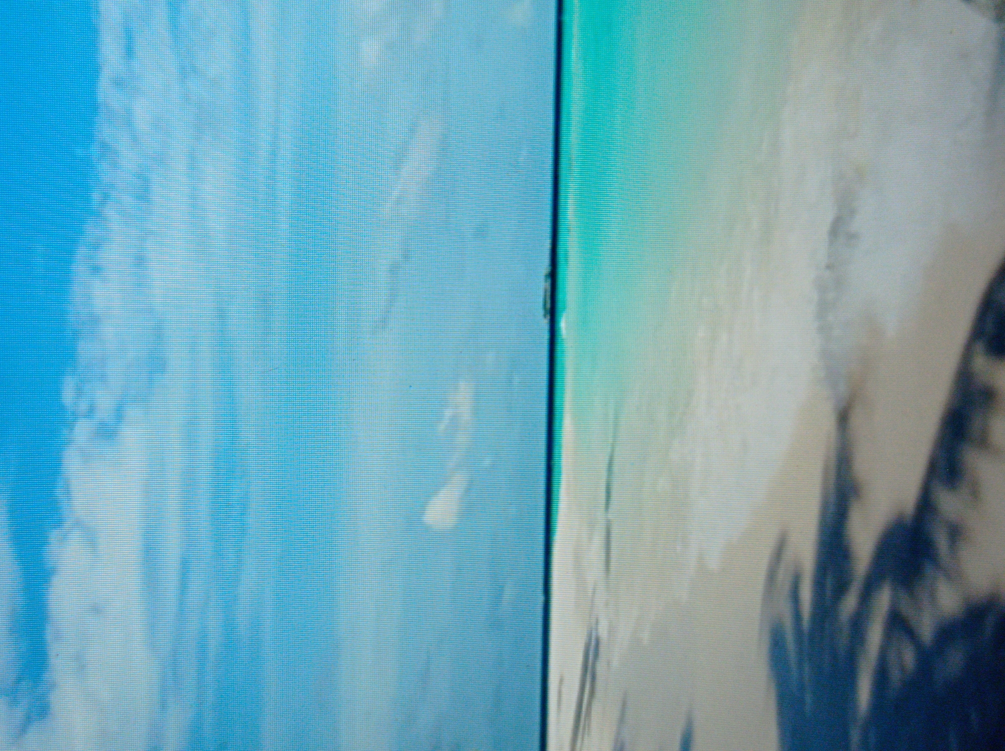 The image displays a serene beach scene with a clear blue sky filled with scattered white clouds. A thin, dark line separates the sky from the turquoise ocean. The foreground consists of a sandy beach, with dark shadows of palm trees cast across it, suggesting a sunny day. In the distance, a small boat or vessel is visible on the horizon. The scene conveys a tropical or subtropical coastal environment. The location is not in Mukachevo, Ukraine, as this is a coastal scene and Mukachevo is an inland city.