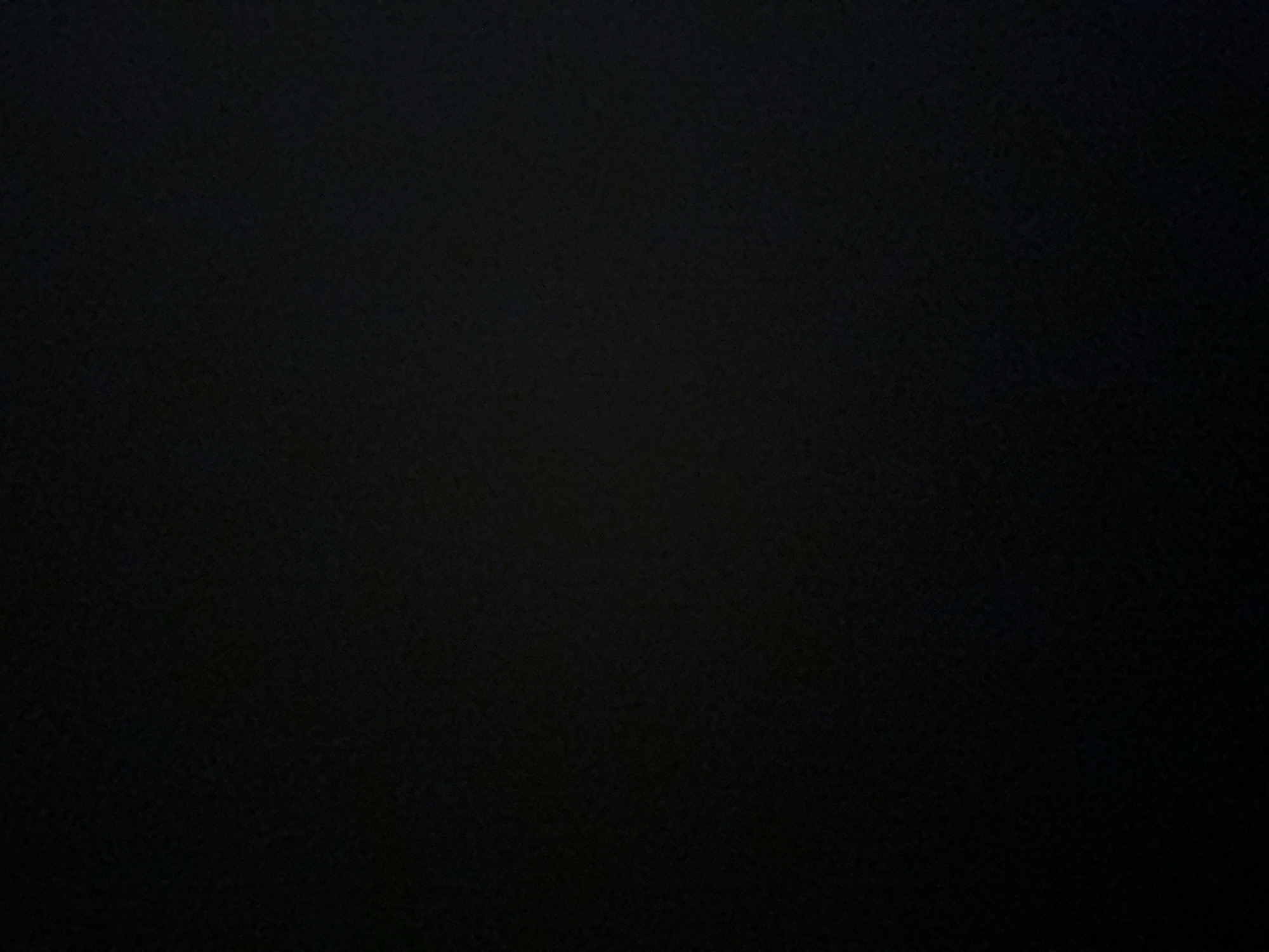 The image is a close-up, slightly blurry shot of a dark, textured surface. The texture appears to be a rough fabric, possibly velvet or a similar material, with a subtle pattern of lighter and darker fibers that catch the light unevenly. The overall impression is one of deep shadow and muted tones, with no distinct subjects, objects, or discernible scene. The darkness of the image prevents any details about time of day, weather, location, or emotions from being observed. There is no visible text. The provided crops offer slightly different perspectives on the same dark, textured surface, reinforcing the impression of a close-up view of a fabric.