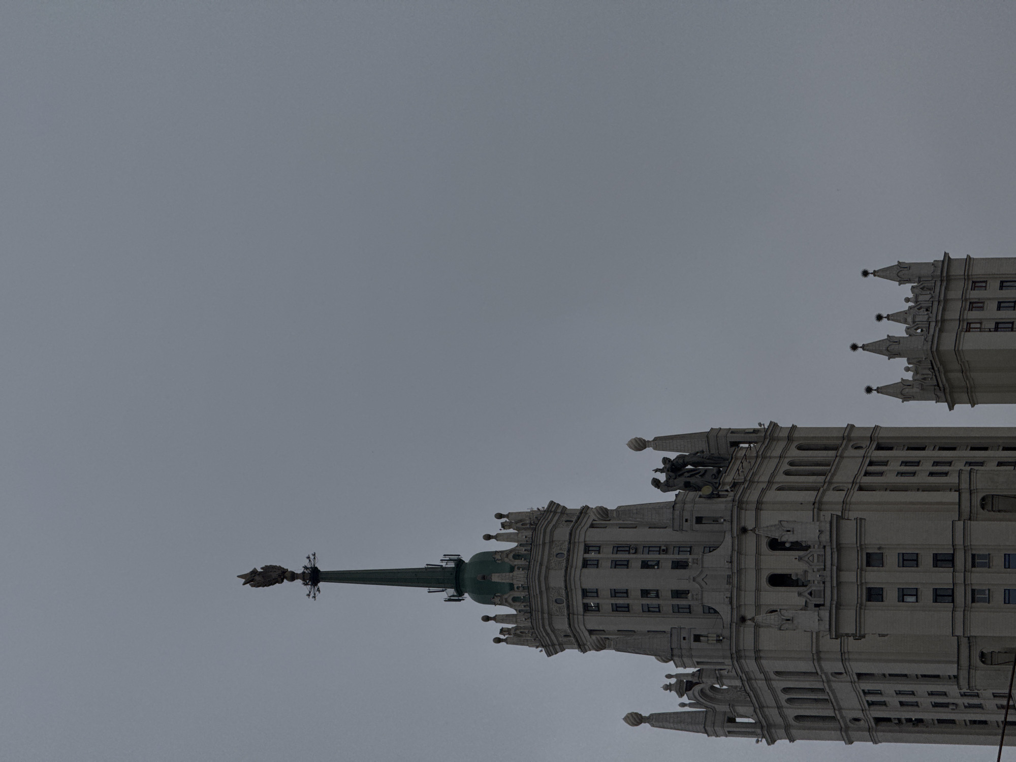 The image shows two towers of the Kotelnicheskaya Embankment Building in Moscow, Russia. The towers are white with many windows. The sky is grey.