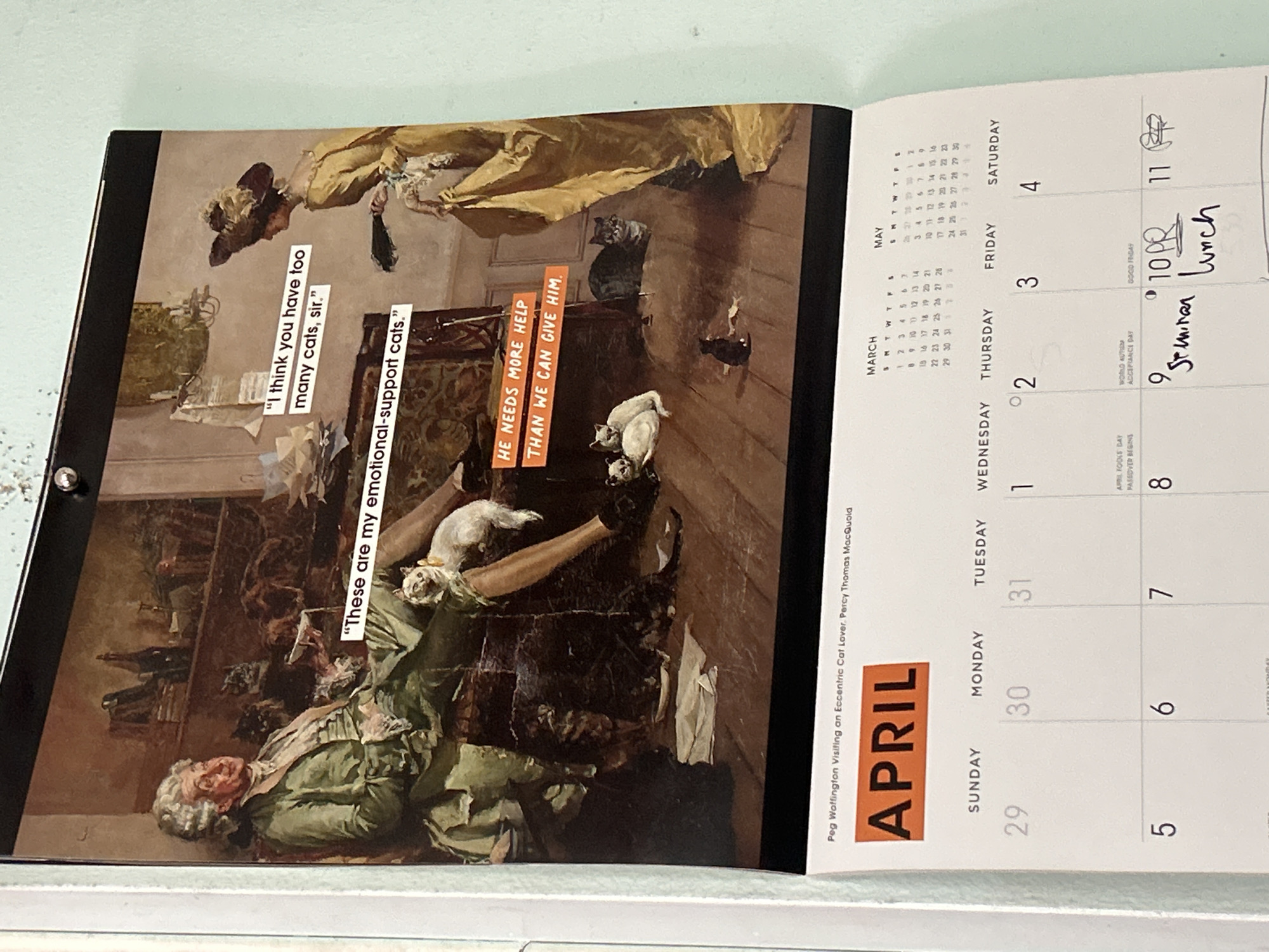 An open calendar, rotated counter-clockwise, displays the month of April. The left page features a classical-style painting titled "Peg Waffington Visiting an Eccentric Cat Lover" by Percy Thomas MacQuoid. The artwork depicts a woman in period attire, possibly expressing surprise or concern, standing over a seated man who is surrounded by multiple cats. Several cats are visible on the man's lap, table, and floor.
Superimposed text bubbles on the painting present a humorous dialogue: the woman's speech bubble reads, "I think you have too many cats, sir." The man's reply is, "These are my emotional-support cats.” An orange block of text further states, "HE NEEDS MORE HELP THAN WE CAN GIVE HIM."
The right page shows the April calendar grid for the days March 29, 30, 31, and April 1, 2, 3, 4. Smaller calendars for March and May are also visible. Notable dates include "APRIL FOOLS DAY PASSOVER BEGINS" on April 1, "WORLD AUTISM ACCEPTANCE DAY" on April 2, and "GOOD FRIDAY" on April 3. Handwritten notes are visible on several days: "9 Seminar" on April 2, "10PR" and "Lunch" on April 3, and "11 PP" on April 4. The calendar is set against a light blue-green background.