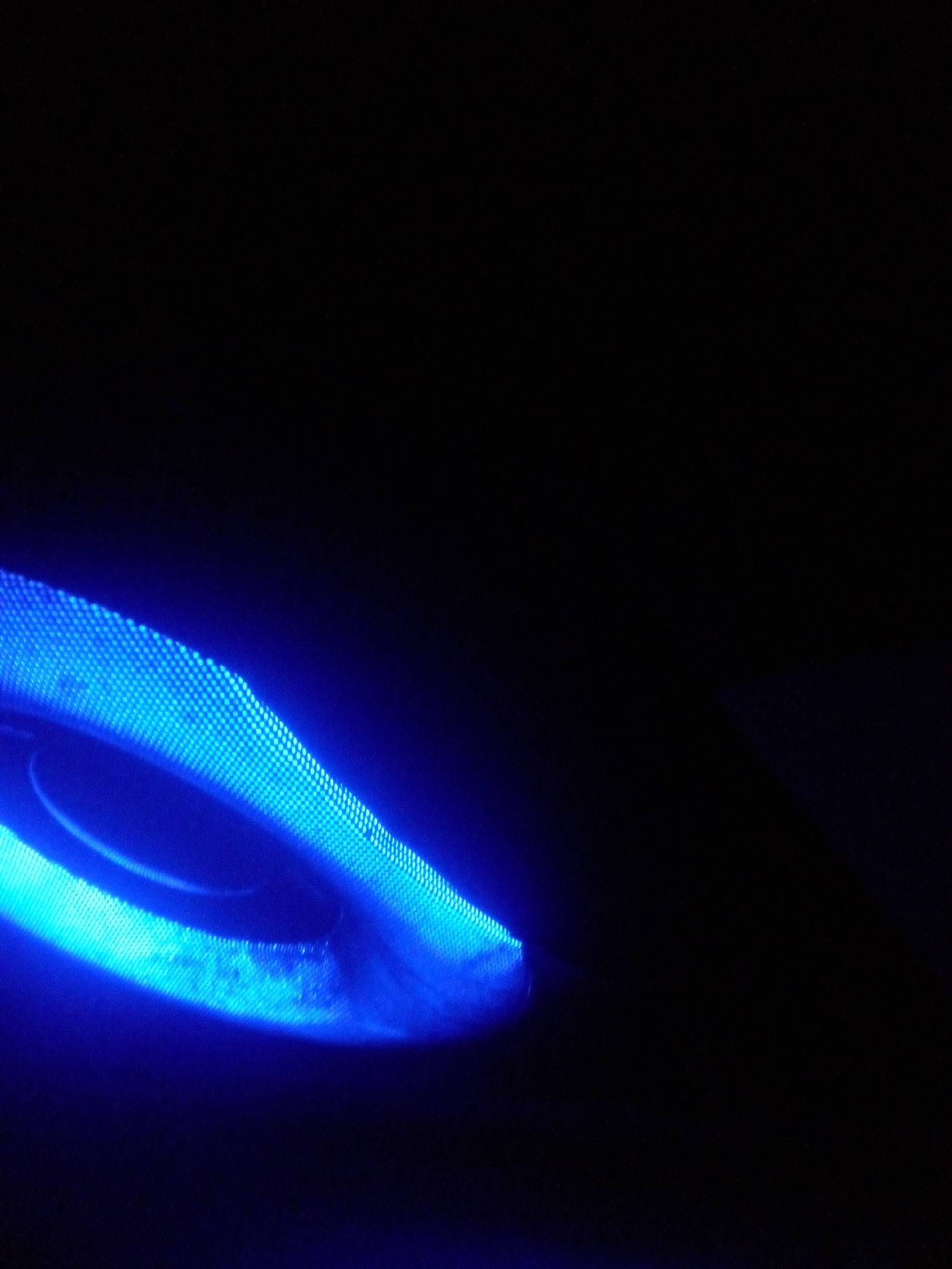 The image shows a close-up, abstract view of a blue light emanating from a circular object, likely a speaker or light fixture, against a dark background. The light has a pixelated texture and casts a glow that illuminates a portion of the surrounding darkness. No people or specific landmarks of Nyanya, Nigeria are visible.