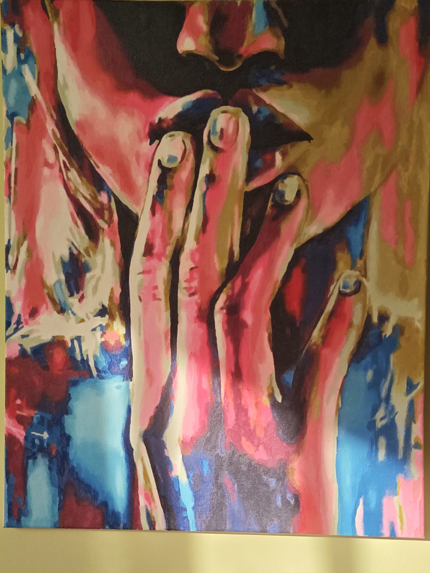 This is an abstract painting with bold strokes of pink, blue, and gold, depicting a close-up of a person's face and hands. The focus is on the lips and fingers, with the fingers brought up to the mouth. The background is a dark void, with splashes of color suggesting fabric or other elements. The style is impressionistic and emotive, with a focus on color and form rather than realistic detail. This painting is located in a room with a pale yellow wall. There is no indication of the city of Shcherbinka, Russia, in the image or its context.