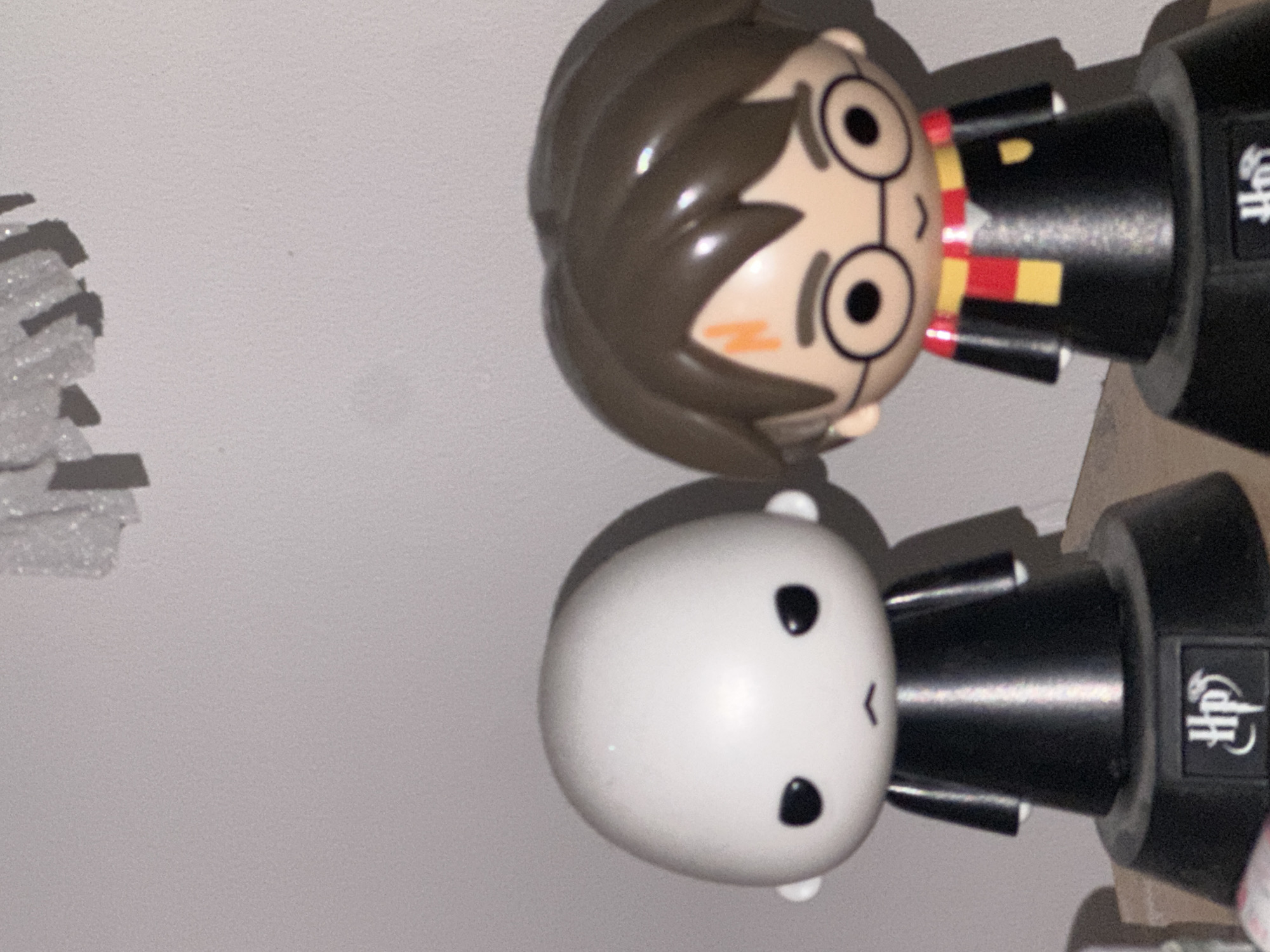 Two Harry Potter figurine toys, one depicting Harry Potter and the other depicting Voldemort, are arranged side by side on a surface. They are situated indoors. A piece of styrofoam is to the left of the toys. The specific location in Budva, Montenegro, is not discernible from the image.