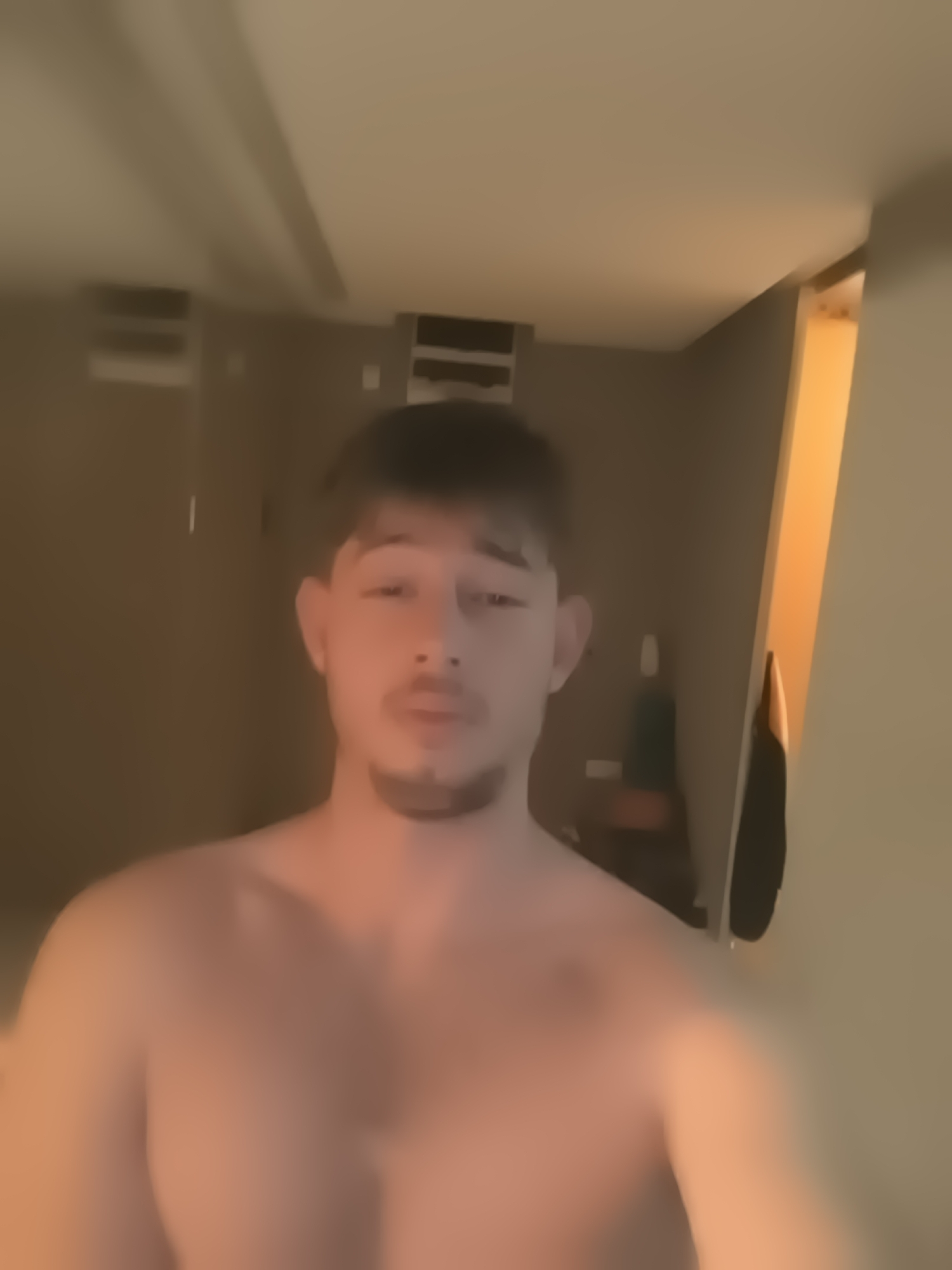 A blurry, low-resolution image shows a shirtless man with short dark hair and a mustache and beard. The background is an indistinct interior with a door frame visible on the right. The location cannot be determined to be Sofia, Bulgaria, or any specific location.