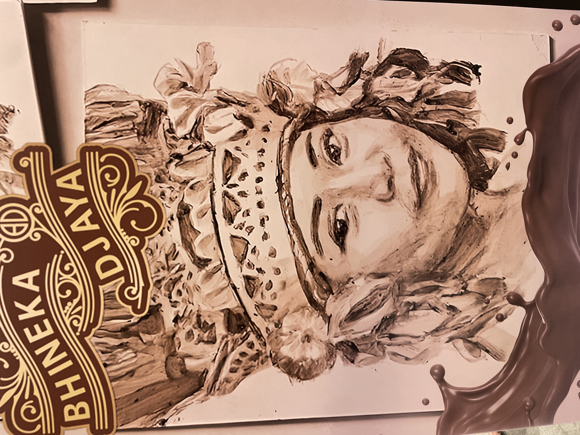 The image shows a painting or drawing of a person with elaborate headwear, possibly historical or theatrical, alongside elements that suggest a chocolate product. The person's face is rendered in a sepia tone, giving it an aged or artistic appearance. To the left of the face is a logo with ornate details and the words "BHINEKA DJAYA." To the right is a large splash or flow of brown, likely representing chocolate. The setting, time, and specific location (city, country) are not discernible from the image. The overall impression is that it is a promotional or artistic depiction related to a chocolate brand named "Bhineka Djaya."