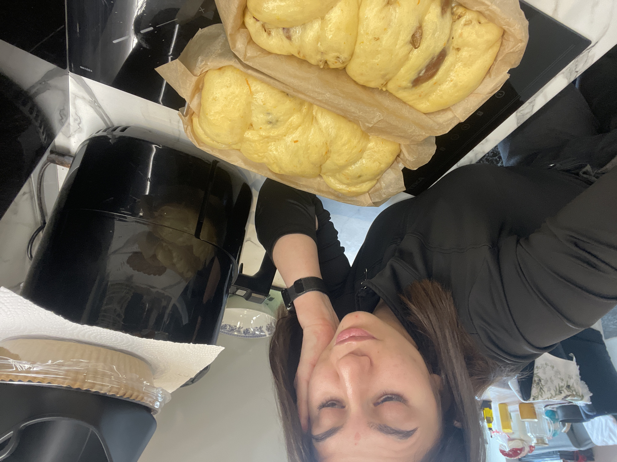 A woman is holding her head and taking a selfie with two loaves of baked bread beside a black air fryer. The bread loaves are in parchment paper. The background shows a black and white checkered stovetop.
The city of Sofia, Bulgaria cannot be identified in this photo.