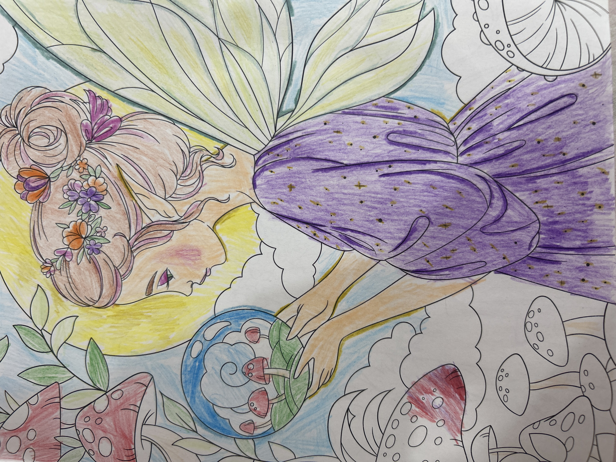 The image is a coloring page featuring a fairy holding a sphere containing miniature mushrooms and grass. The fairy has blonde hair styled in an updo with flowers, wearing a purple dress with gold accents and translucent wings. She is depicted in profile, looking down at the sphere. Surrounding the fairy are large mushrooms, leaves, a crescent moon, and clouds. The coloring appears to be done with colored pencils. There is no indication of a specific location in Novorossiysk, Russia, or any real-world setting.