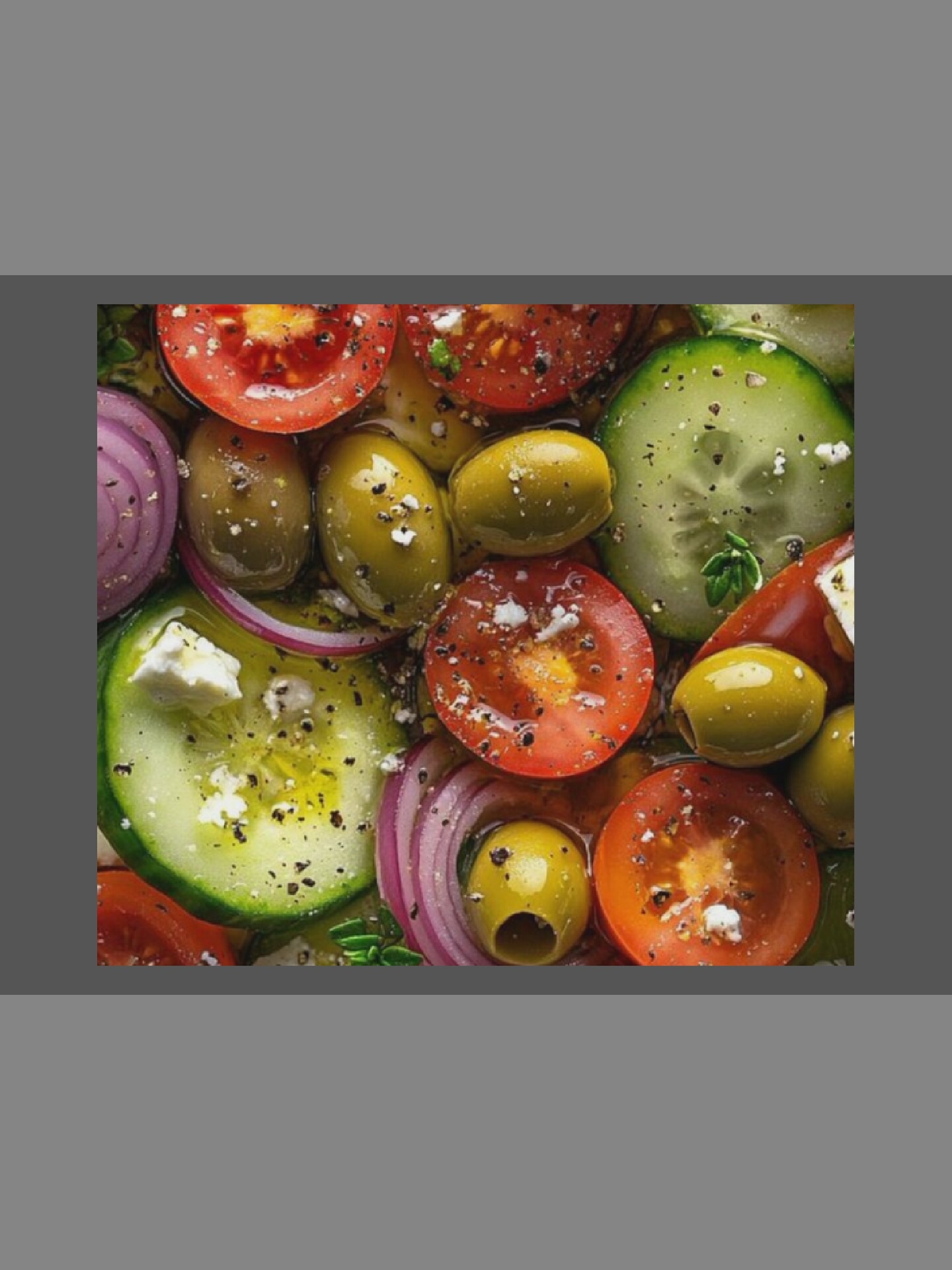 A close-up overhead shot shows a Greek salad. The salad is composed of sliced tomatoes, cucumbers, Kalamata olives, and red onions, all tossed in a vinaigrette dressing. Some of the ingredients are sprinkled with feta cheese and black pepper. The lighting is bright, and the colors are vibrant, making the salad appear fresh and appetizing. The salad is presented in a bowl or platter, but the container is not fully visible.