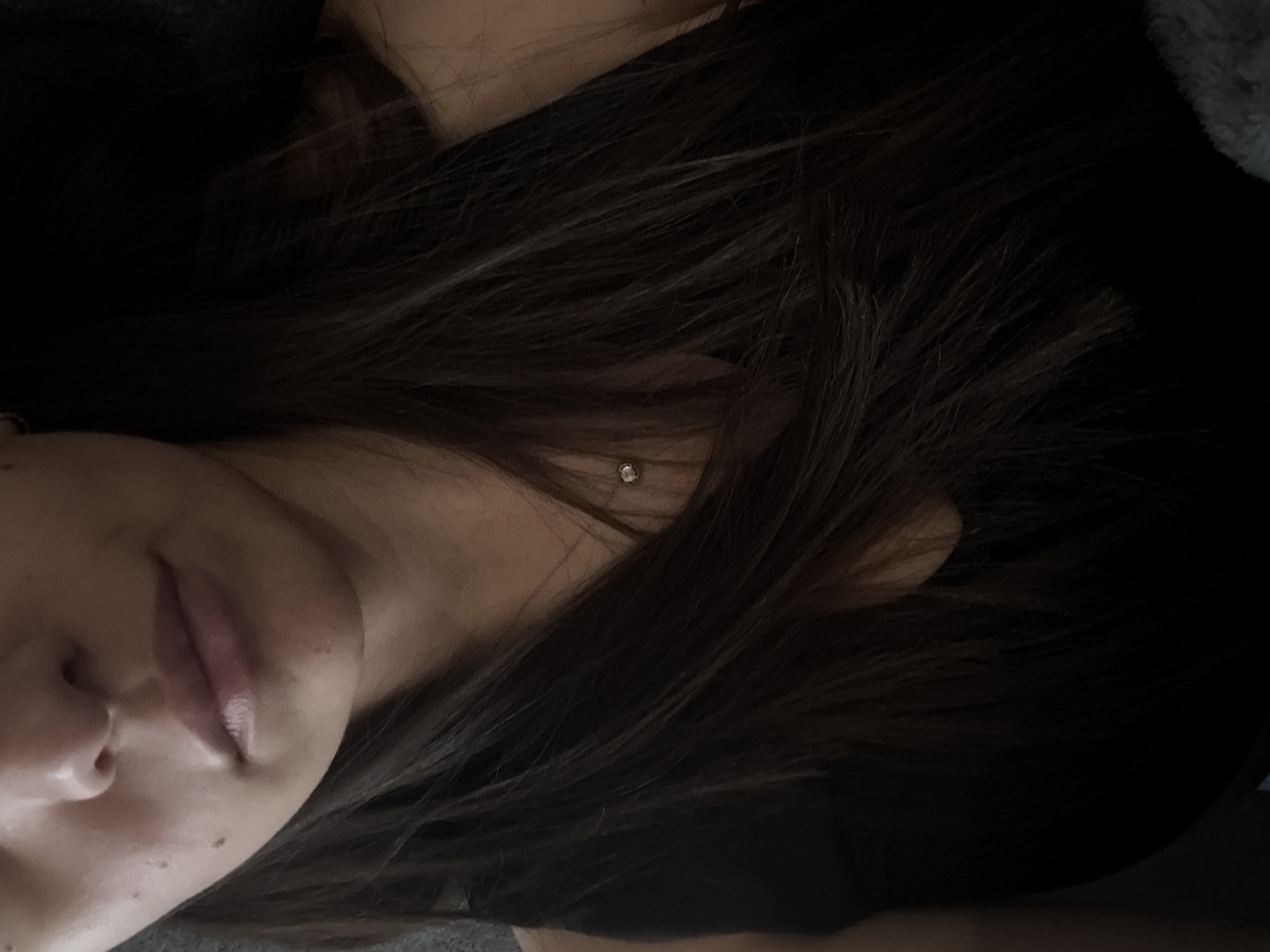 The image shows a close-up view of a person's face and hair. The person has dark hair, which is partially covering their face. The focus is on their nose and lips. There appears to be a small earring visible near the ear. The background is dark. The image does not provide any information related to the location in the city of Yerevan, Armenia.