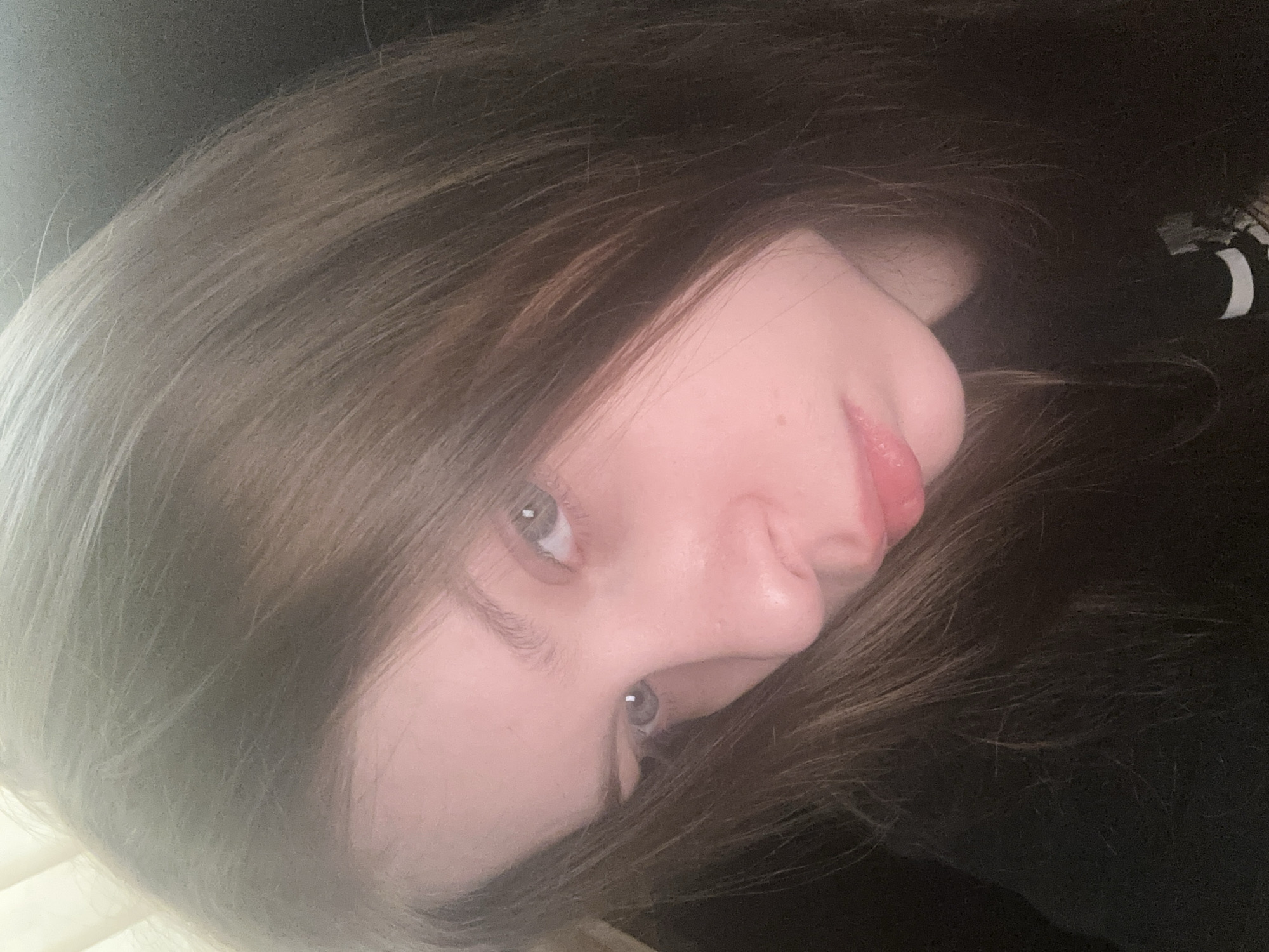 A close-up, angled portrait of a young person with fair skin, brown hair, and light-colored eyes. The person is looking toward the camera. The background is dark and out of focus. There is no information that suggests the photo was taken in Moscow, Russia.