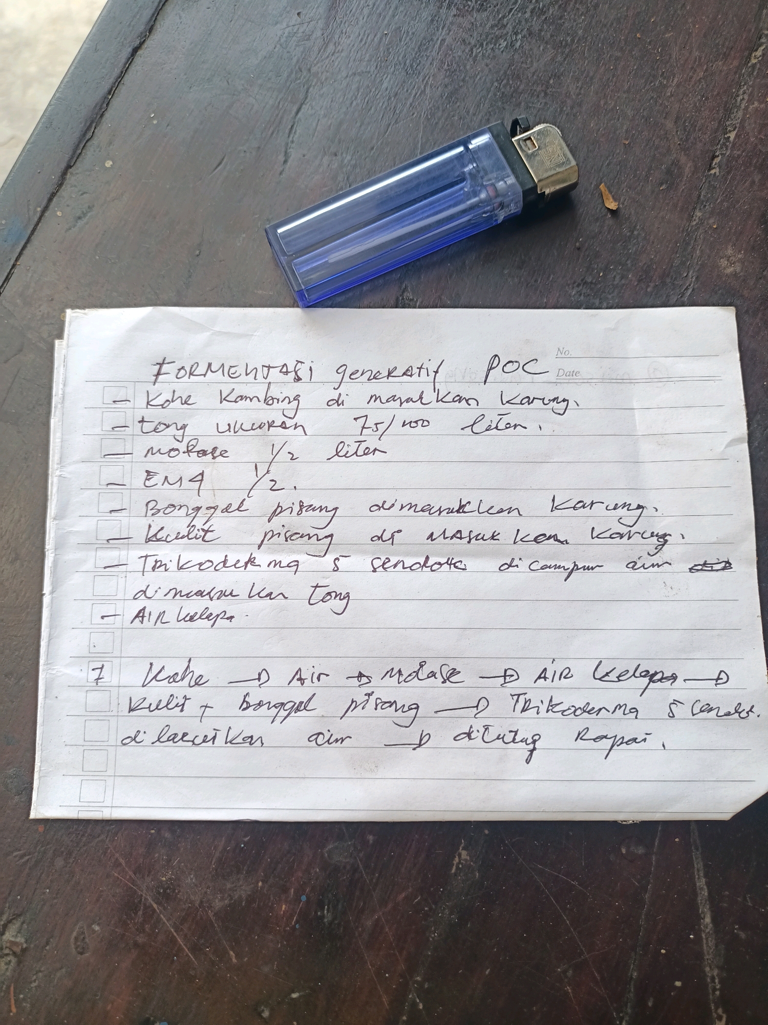 The image shows a close-up, eye-level view of a handwritten list on lined paper. The paper is placed on a dark, textured surface that appears to be wood, possibly a table. A transparent blue lighter is positioned on the paper, slightly to the upper right of the center. The list has checkboxes next to some items and is written in dark ink. The writing details ingredients and steps for something called "FERMENTASI generatif POC". Some visible items include "Kohe Kambing" (goat manure), "molase" (molasses), "EM4", "Bonggol pisang" (banana stem), and "kulit pisang" (banana peel). There is also a numbered item "7" followed by "Kahe" and other ingredients. The paper itself shows some creases and wear. The scene is devoid of any identifiable landmarks or elements that would indicate a specific location within the city of Trenggalek, Indonesia, or any other city.