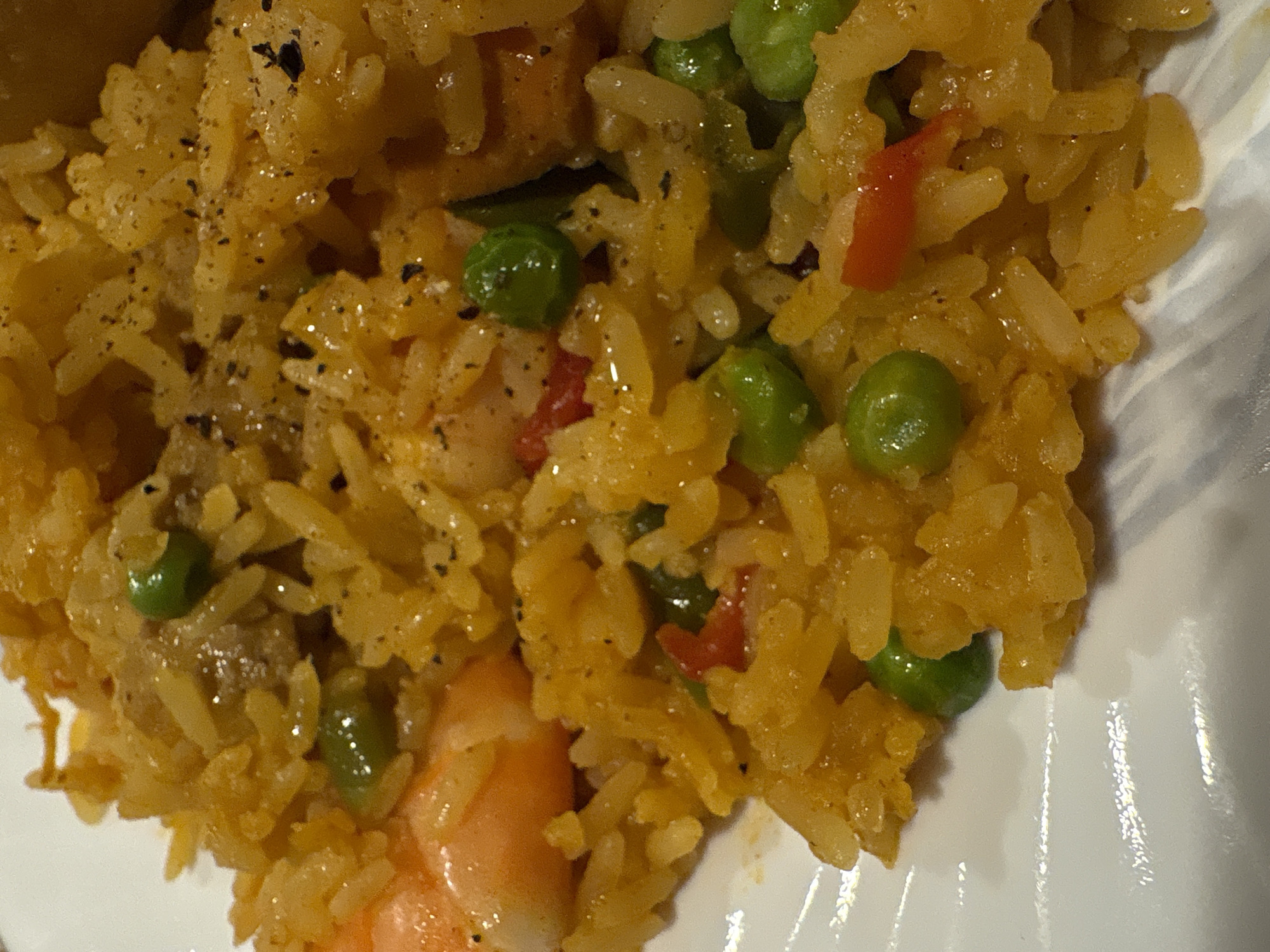 A close-up shot of a plate of yellow rice with peas and shrimp. There are also small pieces of red bell pepper in the rice. Black pepper is sprinkled on top. The plate appears to be white. The location and any contextual information about Mexico City are not discernible from the image.