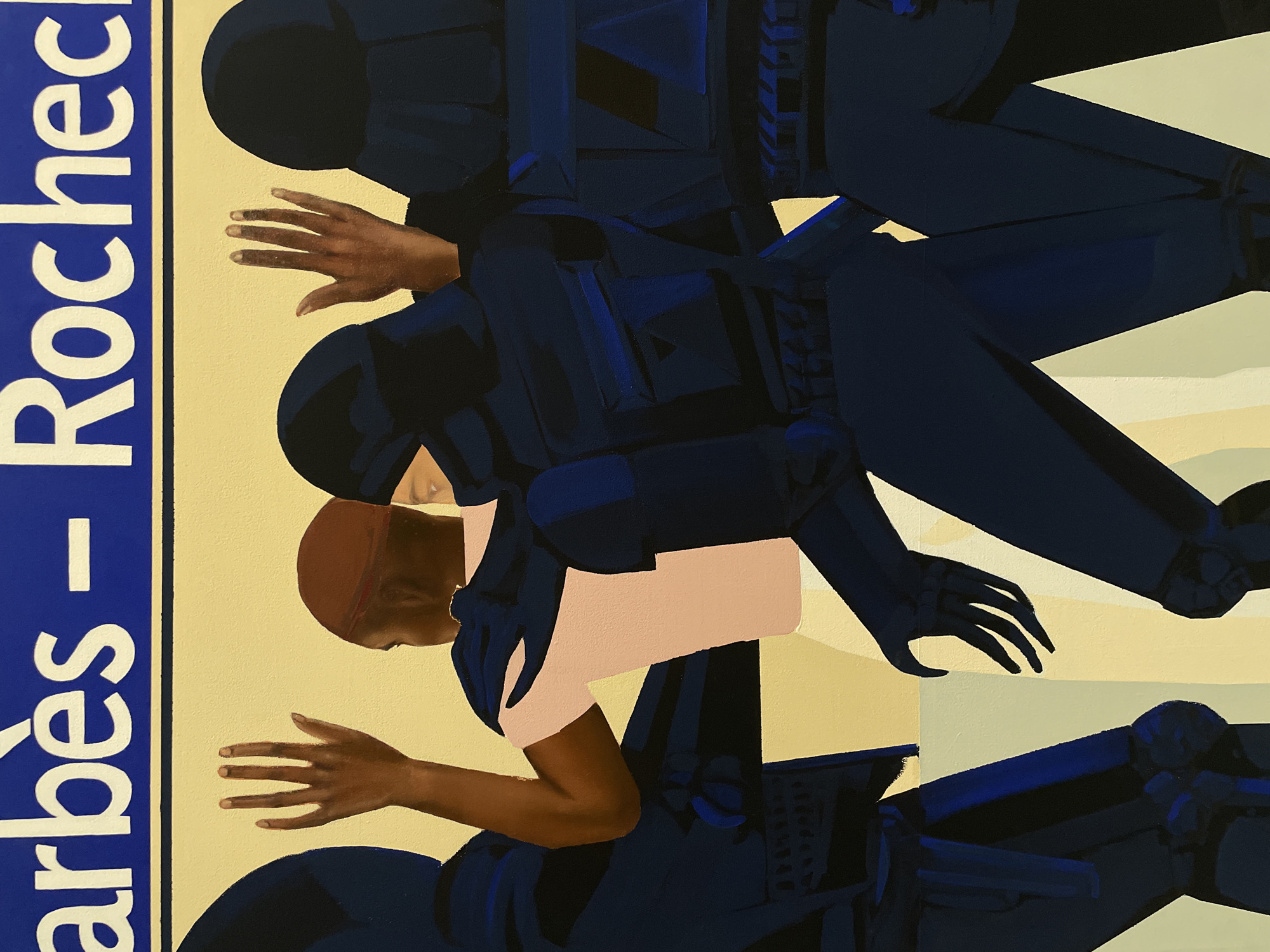This painting depicts a scene at the Barbès - Rochechouart metro station in Paris, France. A central figure with dark skin, wearing a light pink short-sleeved shirt and a dark brown head covering, stands with both hands raised above their head, palms facing forward. They are partially obscured by and surrounded by at least three other figures dressed in dark blue, tactical-style uniforms with helmets that cover their faces, though one eye is visible on the figure to the right of the central person. One uniformed figure has an arm around or near the central figure's back, while another's hand is raised similarly to the central figure's. The background is a plain light yellow, topped by a blue sign with white capital letters clearly displaying "Barbès - Rochechouart," identifying the location. The overall composition suggests a tense interaction or confrontation.