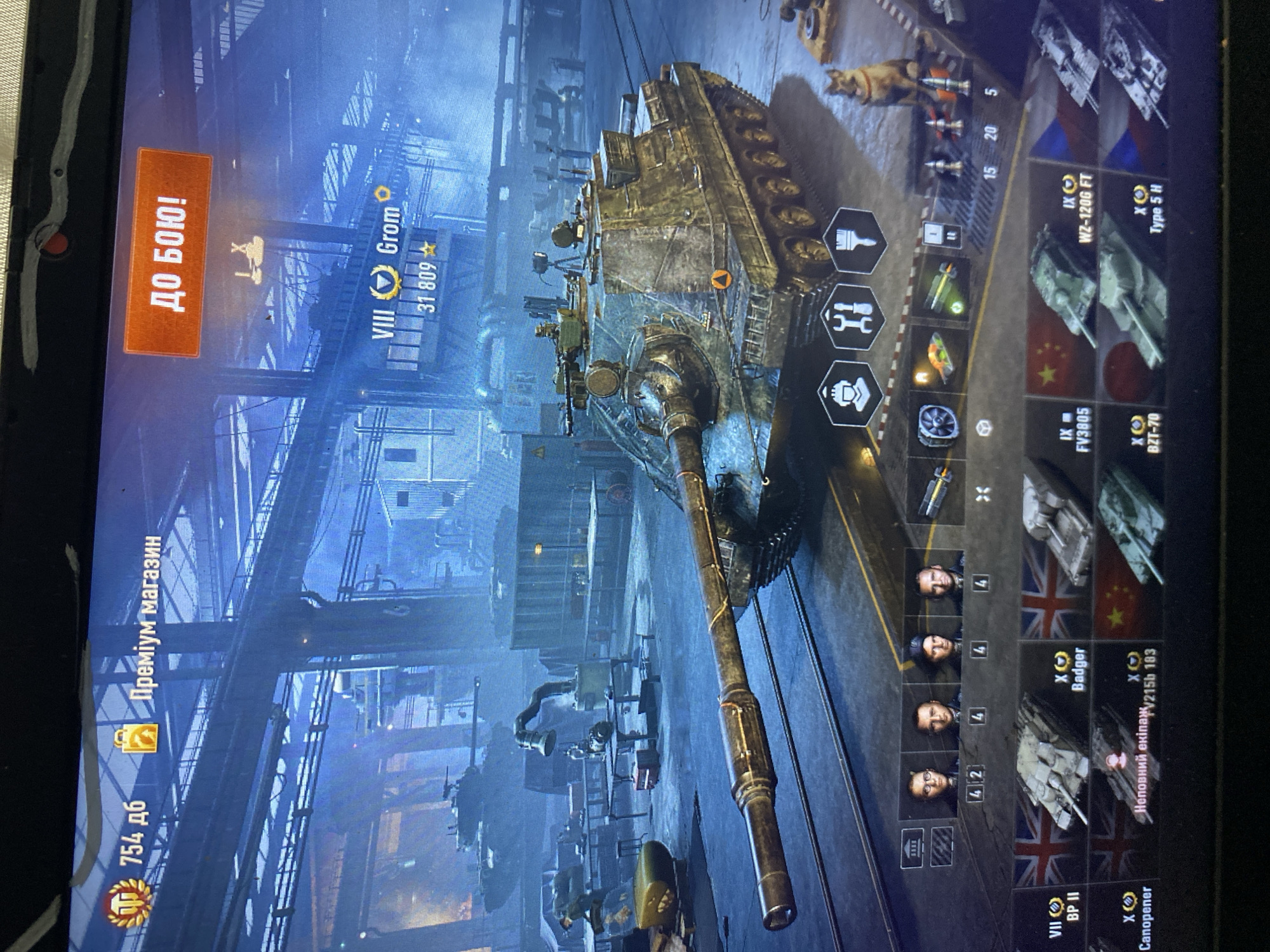 The image is a screenshot of a video game's garage screen, likely a tank simulation game like World of Tanks. It displays a virtual environment with a detailed tank in the foreground, set within a dimly lit, industrial-style hangar. Various game interface elements are visible, including currency or experience points (754 дб), a "Premium Shop" button (Преміум магазин), and a "To Battle!" button (ДО БОЮ!). Information about a specific tank, "Grom" of VIII tier, with a player score of 31,809, is prominently displayed. Below the tank, there are icons representing different game functions and a selection of other tanks with their tier levels and names, such as "BP II," "Badger," "Canopener," "FV3805," "WZ-120G FT," "BZT-70," and "Type 5 H." The image does not provide any information or visual cues to suggest a specific location in the city of Szczecin, Poland, or any real-world geographical context.
