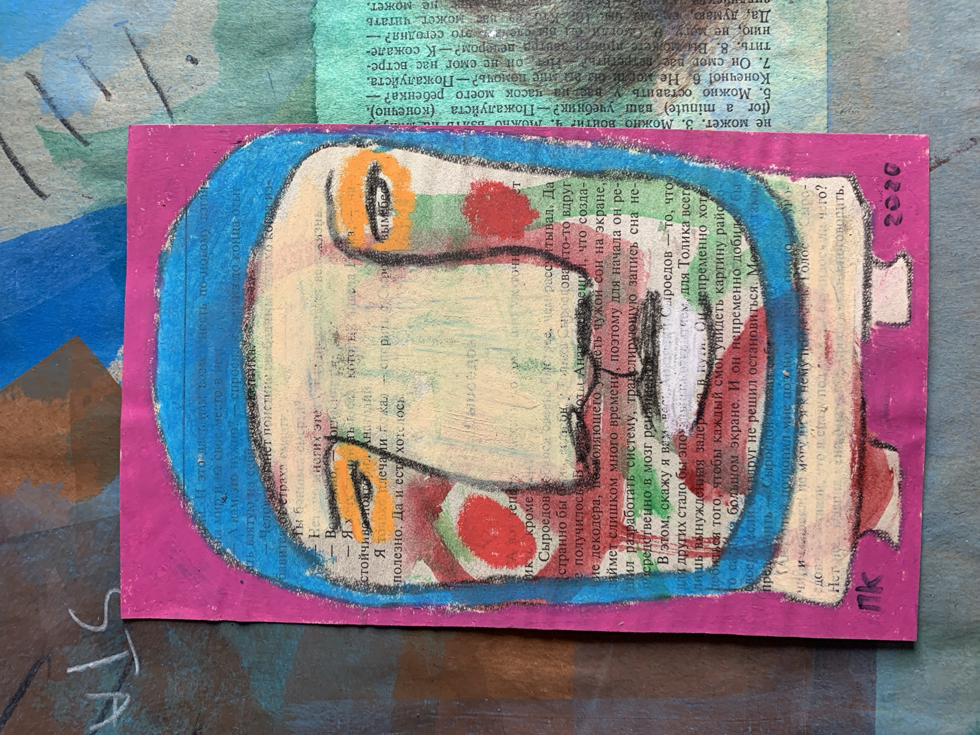 This is a close-up, eye-level, mixed-media collage artwork featuring a stylized portrait of a person with a blue head covering. The face is rendered with bold lines and vibrant colors, including orange around the eyes and red on the cheeks. The background is a collage of textured papers, including what appears to be pages from a book with Russian text. The overall aesthetic is abstract and expressive. The artwork does not depict any specific location in Sergeevo, Russia, nor does it provide any forensic details of a scene.