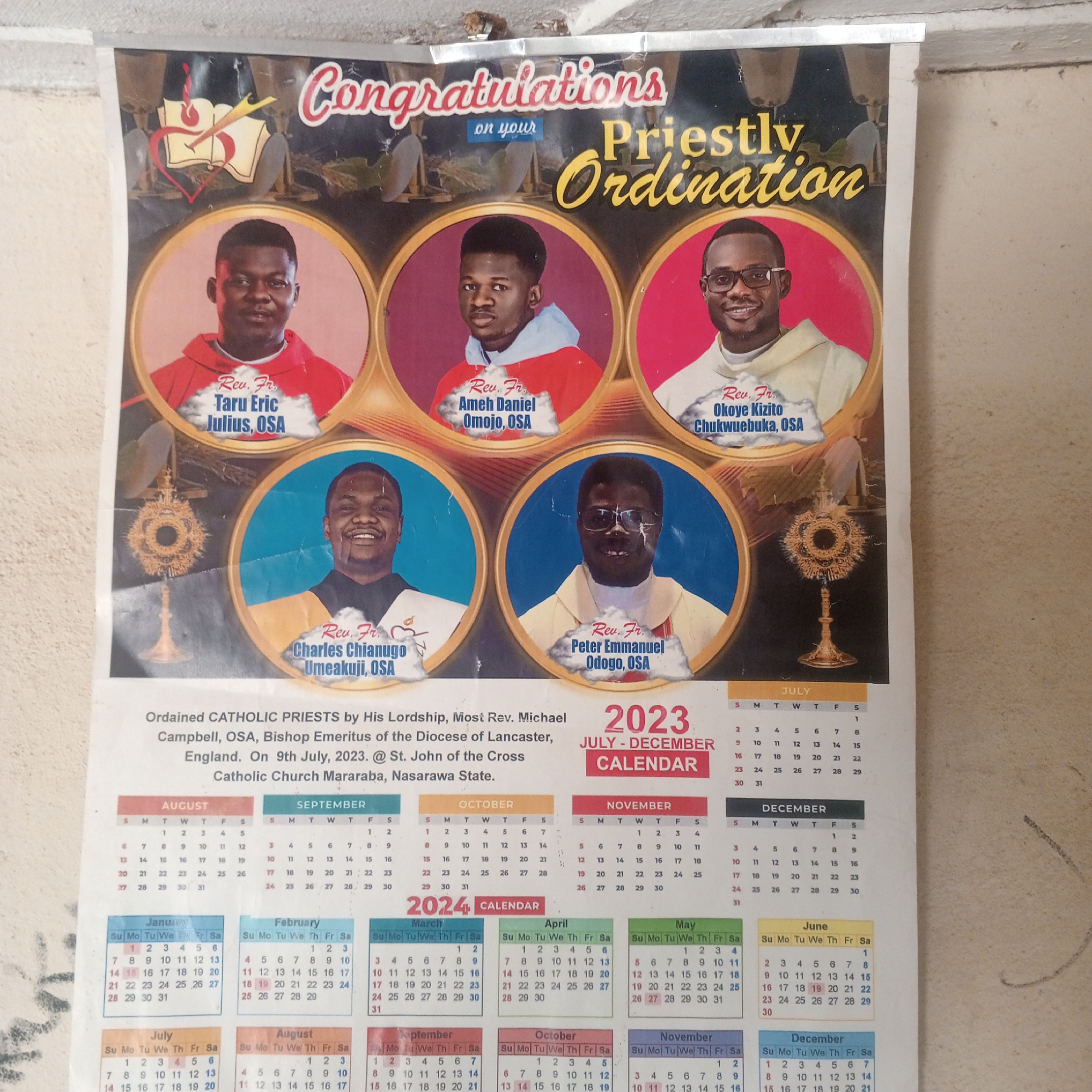 The image shows a calendar poster for the second half of 2023 and the first half of 2024, commemorating the priestly ordination of five individuals. The top of the poster features the text "Congratulations on your Priestly Ordination" in decorative fonts. Below this are five circular portraits of the ordained priests. From left to right, they are: Rev. Fr. Taru Eric Julius, OSA; Rev. Fr. Ameh Daniel Omojo, OSA; Rev. Fr. Okoye Kizito Chukwuebuka, OSA; Rev. Fr. Charles Chianugo Umeakuji, OSA; and Rev. Fr. Peter Emmanuel Odogo, OSA. In the center of the poster, to the left of the bottom row of portraits, is an image of a monstrance.
The text below the portraits states: "Ordained CATHOLIC PRIESTS by His Lordship, Most Rev. Michael Campbell, OSA, Bishop Emeritus of the Diocese of Lancaster, England. On 9th July, 2023. @ St. John of the Cross Catholic Church Mararaba, Nasarawa State."
The calendar section displays the months of July to December 2023, and January to June 2024. The specific location mentioned is Mararaba, Nasarawa State, which is a town in Nigeria.