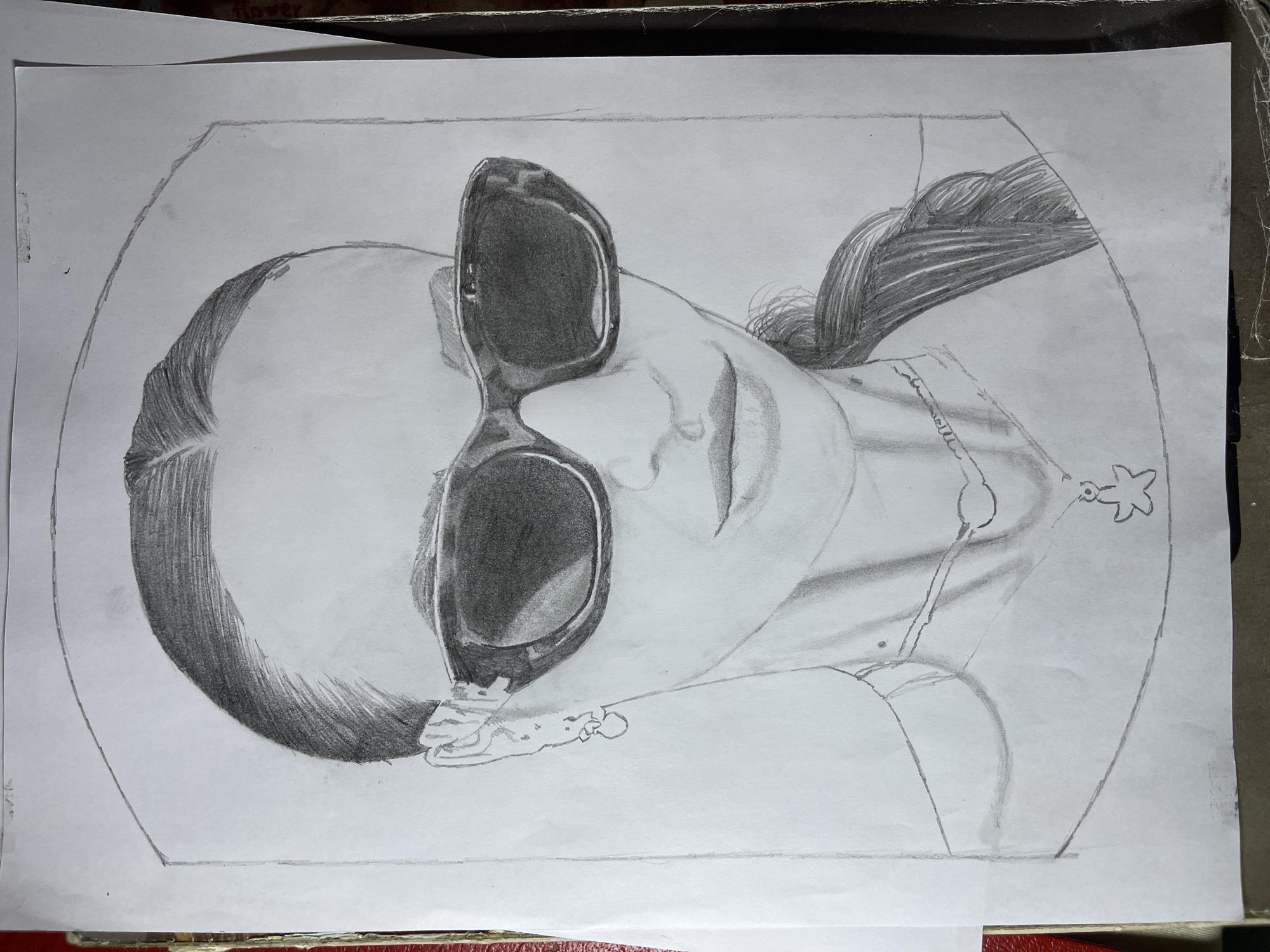 A pencil sketch depicts a person wearing sunglasses. The subject is positioned within an oval border. The individual's hair is styled in a bun, with the remaining hair draped over their shoulder. A necklace with a pendant is visible. A hand rests near the sunglasses. The setting and location, Jos, Nigeria, cannot be discerned from the image.