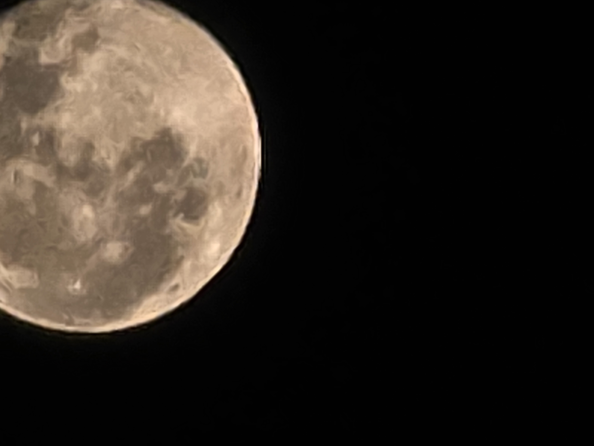 The image is a close-up, vertical shot of the full moon against a black background of the night sky. The moon occupies the upper half of the frame, displaying visible craters and surface features with varying shades of light and dark gray, and a hint of beige. The lower half of the image is completely black. There are no visible landmarks, buildings, or any indication of the city of Sofia, Bulgaria. The image solely focuses on the celestial body.