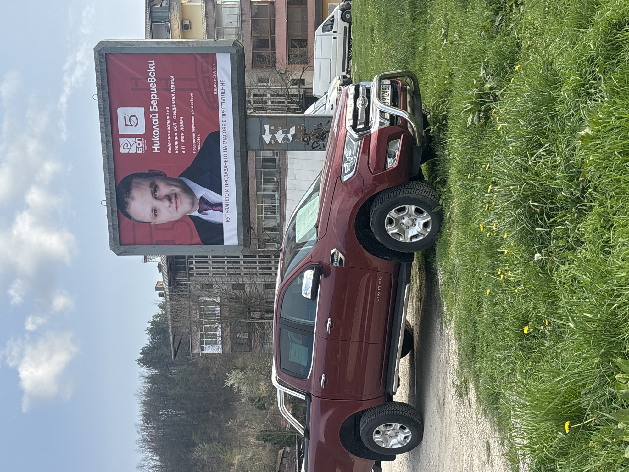 The image depicts a burgundy Ford Ranger truck parked on a dirt road next to a grassy area. Behind the truck is a large billboard featuring a portrait of Nikolai Berievski, a candidate for the coalition BSP - Obedinena Levica in the 11th MIR Lovech district for the snap parliamentary elections of April 9, 2026. The billboard also has the number 5 on it, indicating the candidate's position on the ballot. In the background are buildings and trees. The location is inferred to be in Troyan, Bulgaria, based on the billboard's content and the license plate. A white van is visible further back.
