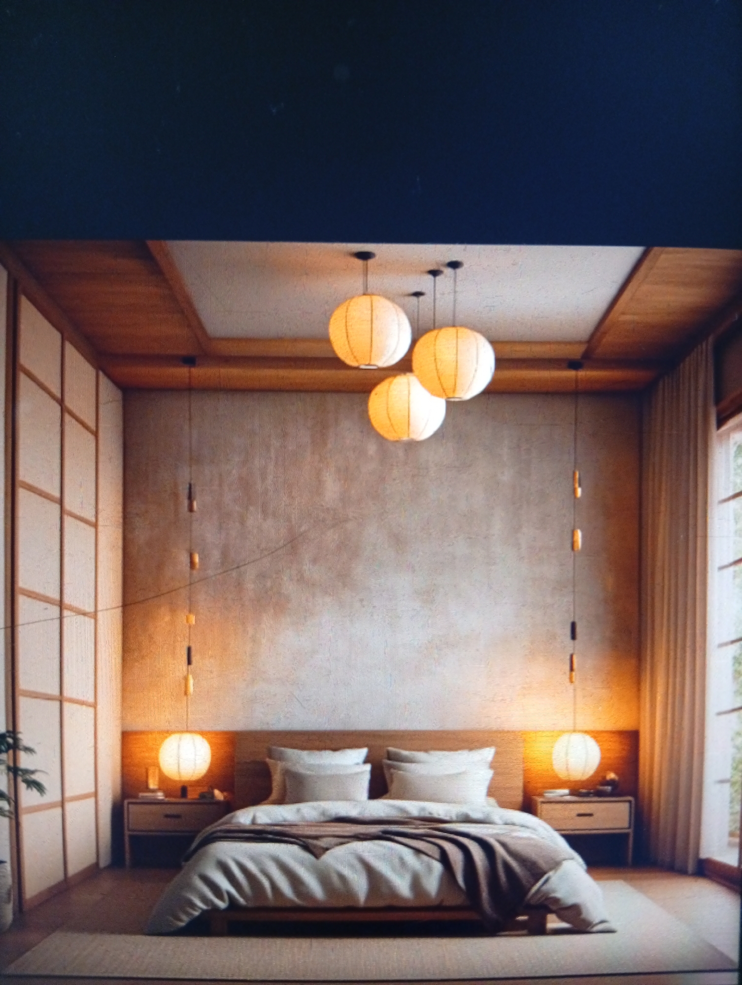 The image depicts a serene bedroom interior. The design aesthetic is distinctly Japanese, featuring sliding shoji screen-style panels on the left wall and wooden framework accents. A bed occupies the center of the room, with a low-profile wooden frame and layered bedding in neutral tones. Above the bed, three round paper lanterns hang at varying heights, providing soft lighting. Two additional, smaller paper lanterns are suspended from the ceiling, one on each side of the bed, illuminating the bedside tables. The walls are a textured, neutral color. A window with light-colored curtains is visible on the right side of the frame, letting in natural light. A large area rug in a natural fiber material covers much of the floor. There are no people visible in the scene. The image doesn't appear to be taken in Dutsen Alhaji, Nigeria, as the architecture and interior design are not typical of that region.