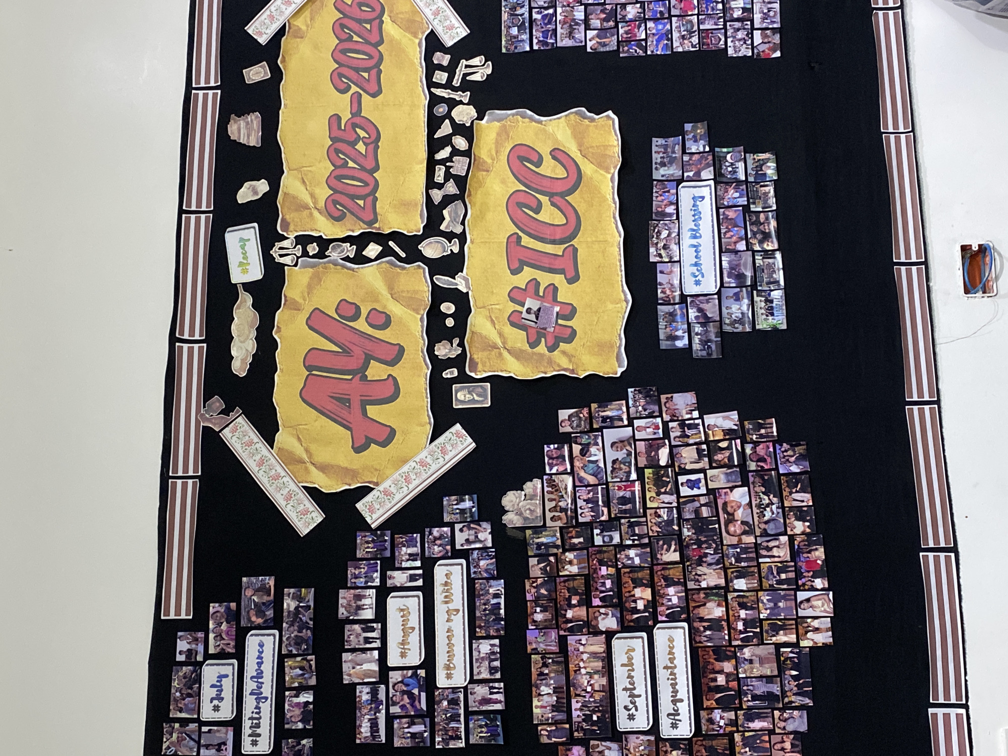 This image captures a vibrant, handmade memory board, likely displayed indoors in Davao City, Philippines. The board is made from black fabric or paper, serving as a backdrop for numerous small, printed photographs and various paper cutouts. The subjects of the photos are predominantly groups of people, presumably students and possibly faculty, captured in candid and posed moments, suggesting school or community events.
Prominently featured are large, crinkled yellow paper cutouts with bold red text. One reads "AY: 2025-2026," indicating an academic year. Another large cutout displays "#ICC," likely an acronym for a school or institution. Decorative elements include brown and white striped borders along the left and right edges, and smaller floral patterned strips.
Numerous smaller paper cutouts with hashtags categorize clusters of photographs. These include "#Recap," "#School Blessing," "#July," "#Miting De Avance," "#August," "#Buwan ng Wika" (Month of Language), "#September," and "#Acquaintance" (referring to an acquaintance party or event). These hashtags and the associated photos illustrate a chronological timeline of school activities and celebrations throughout the academic year. The arrangement of the photos and text suggests a communal effort to commemorate significant moments. An electrical outlet is visible on the white wall to the right, adjacent to the board. The overall impression is a lively display of collective memories from a school or community in the Philippines.