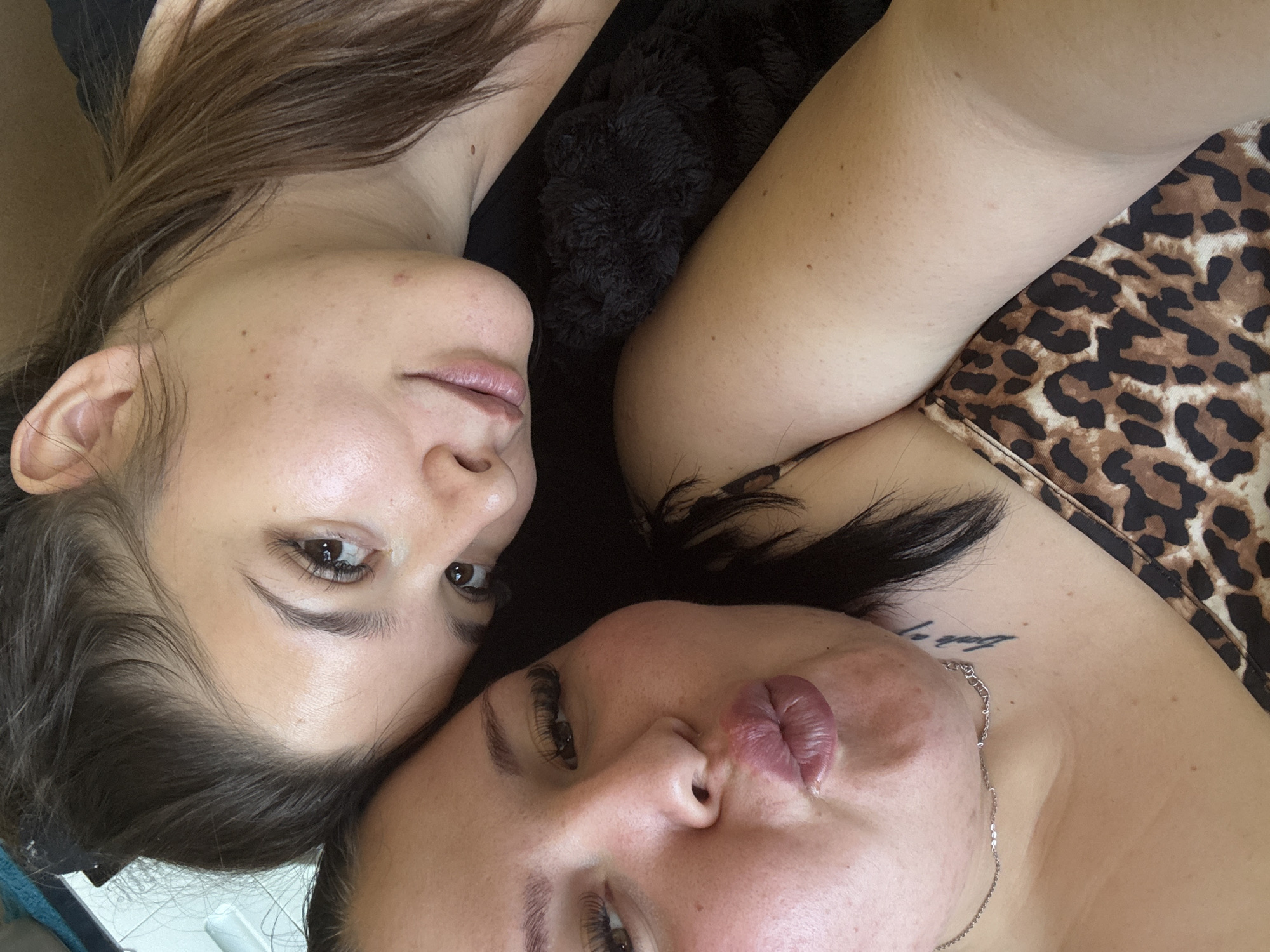 Two women lie close to each other, likely on a bed. The woman on the left has shoulder-length brown hair, clear skin, and light makeup. The woman on the right wears a leopard-print top and has a necklace. The location, Sofia, Bulgaria, is not discernible from the image.