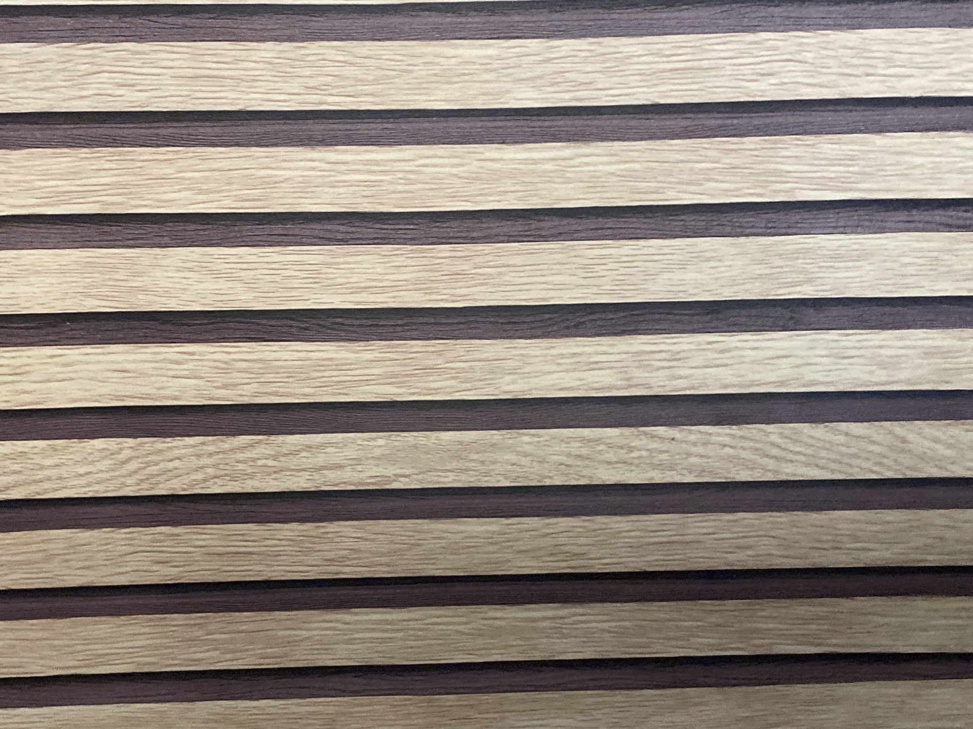 The image displays a close-up view of a textured surface with alternating vertical stripes of light brown wood grain and dark brown. The light brown stripes have a visible wood grain pattern with fine, parallel lines. The dark brown stripes appear smoother and more uniform in color. The overall impression is of a decorative paneling or wallpaper with a natural wood aesthetic. There are no people, animals, or other objects visible in the image, nor is there any indication of its specific location within Jauro Yinu, Nigeria.