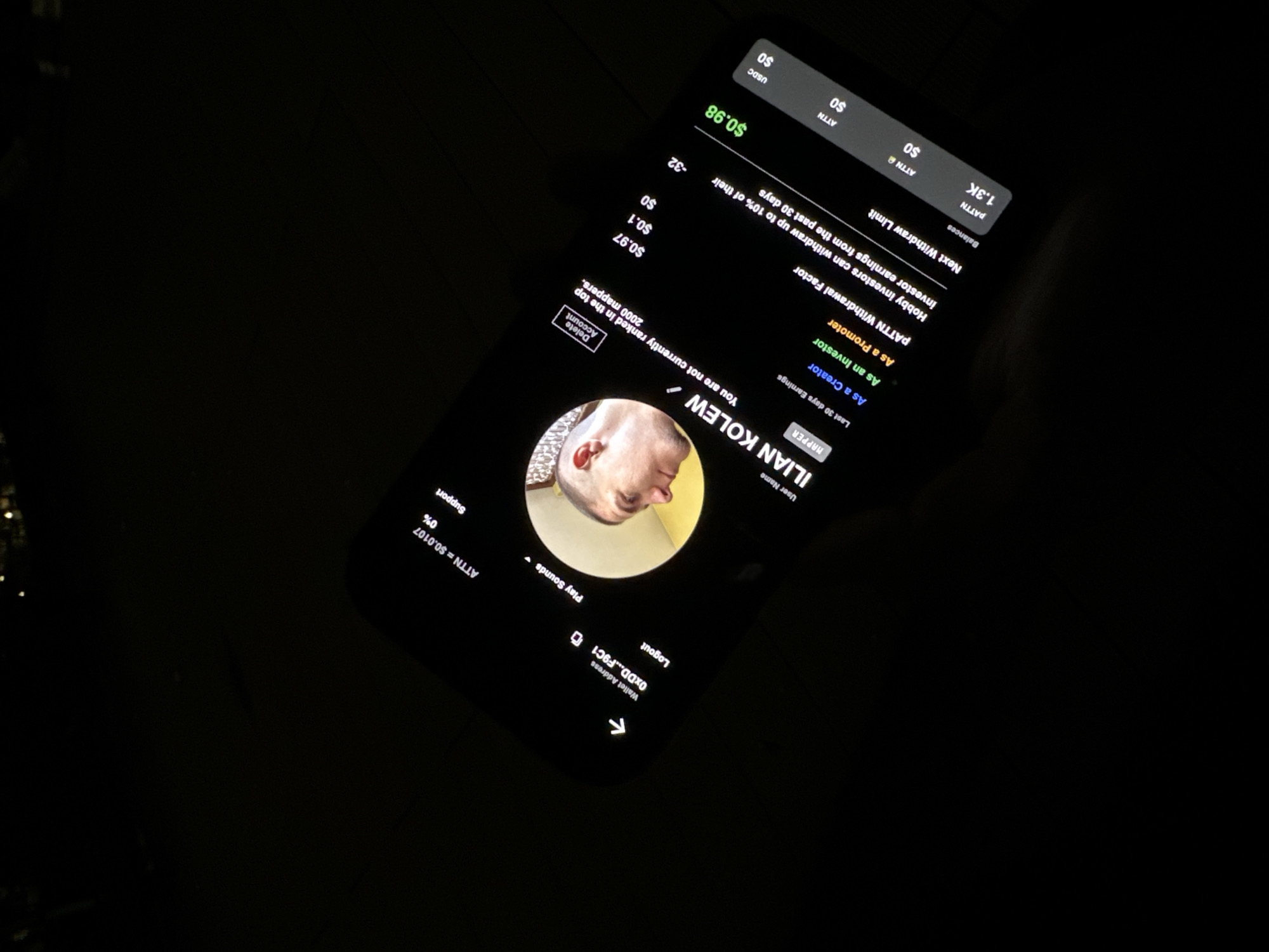 The image shows a mobile phone screen displaying a user profile. The username is "ILIAN KOLEW," identified as a "MAPPER." The profile indicates that the user is not currently ranked in the top 2000 mappers. Recent earnings are listed for "Creator," "Investor," and "Promoter" roles, along with a "PATTN Withdrawal Factor" and a "Next Withdraw Limit." Balances are shown for PATTN, ATTN, ATTN, and USDC. A profile picture is present. The location of the image is not specified.