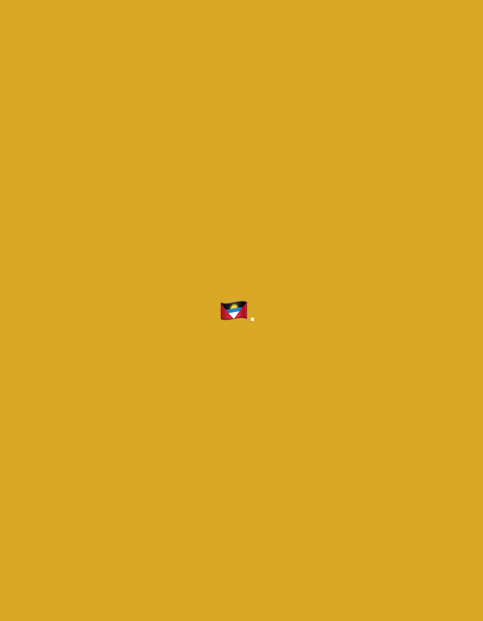 A small, pixelated image of the flag of Antigua and Barbuda is displayed in the center of a solid, ochre-colored background. The flag features a red field with a black band across the top and bottom, containing a white stripe. Within the black band, a stylized sun rises with alternating yellow and white rays. A tiny white square appears to the right of the flag. The image is devoid of any other discernible elements or context. The image does not depict the city of Moscow, Russia.