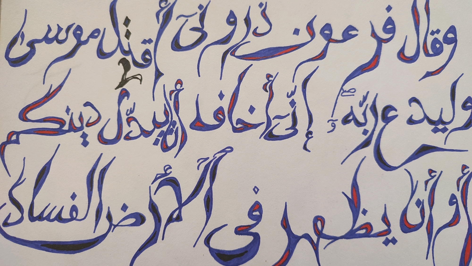 The image displays Arabic calligraphy on a white background. The script is written in blue ink with red and black accents. The text is arranged in several lines, flowing from right to left. There are no people, objects, or environmental elements visible in the image. The calligraphy itself is the sole subject matter. The city of Krasnoye Selo, Russia, is not depicted in the image.