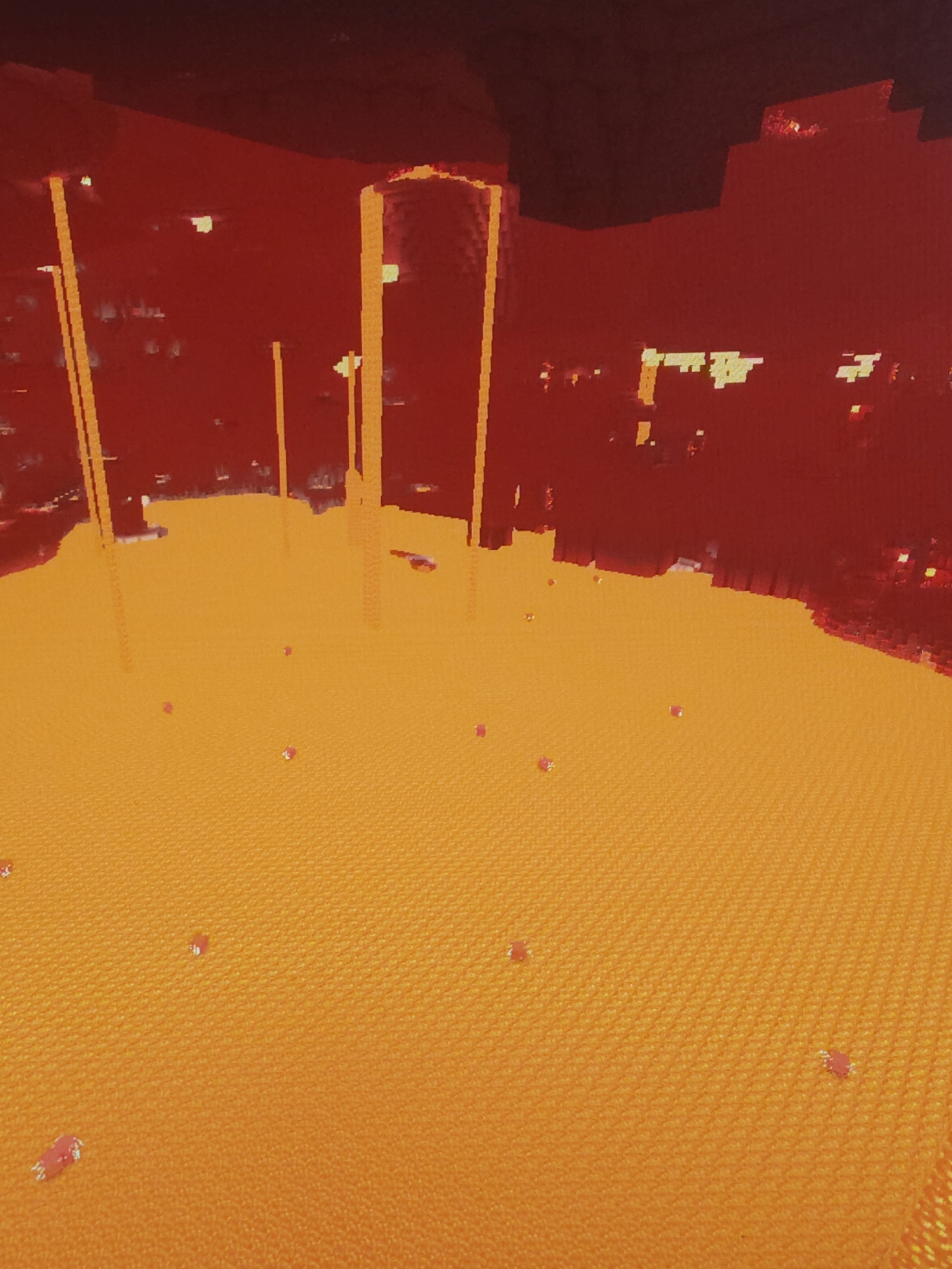 This media file presents a pixelated, block-based environment, characteristic of a video game. The scene is dominated by a vast expanse of vibrant orange-yellow liquid, resembling lava, which covers the foreground and extends into the midground. Surrounding this molten body are imposing dark red, blocky structures that form walls or landmasses, rising sharply into a dark red ceiling, suggesting an enclosed or cavernous space.
Several tall, glowing orange-yellow vertical beams or pillars ascend from the lava's surface or adjacent red terrain, extending upwards and providing the primary light source for the scene. In the distant background, a wider, red architectural structure with a prominent arched opening is visible, also illuminated from within by a similar glow.
Scattered across the surface of the lava are numerous small, irregularly shaped, reddish objects, some with faint white outlines, suggesting distinct entities or effects within the game. The overall lighting is generated solely by the intense radiance of the lava and the glowing pillars, creating a dark, fiery, and otherworldly atmosphere. No discernible human figures or active events are taking place; the scene depicts a static landscape. Based on its blocky aesthetic, lava-filled environment, and distinct color palette, the setting strongly resembles the Nether dimension from the video game Minecraft. There is no visible text in the image.